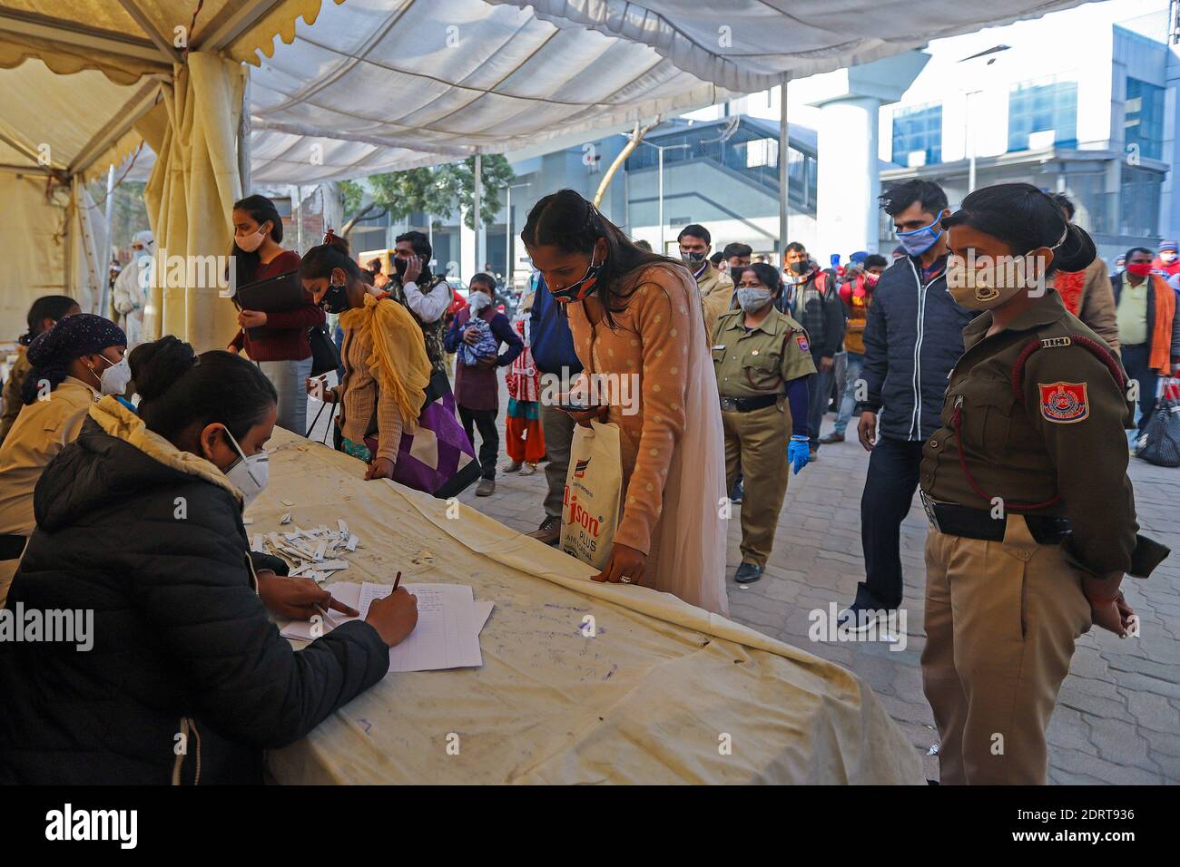 I passeggeri che indossano maschere come misura preventiva contro il coronavirus registrano i loro nomi per sostenere il test Covid19 presso una stazione degli autobus a Delhi. I casi di coronavirus in India hanno attraversato 10 milioni di persone con nuove infezioni che si sono tuffate ai livelli più bassi in tre mesi, mentre il paese si prepara per una massiccia vaccinazione COVID-19 nel nuovo anno. Foto Stock