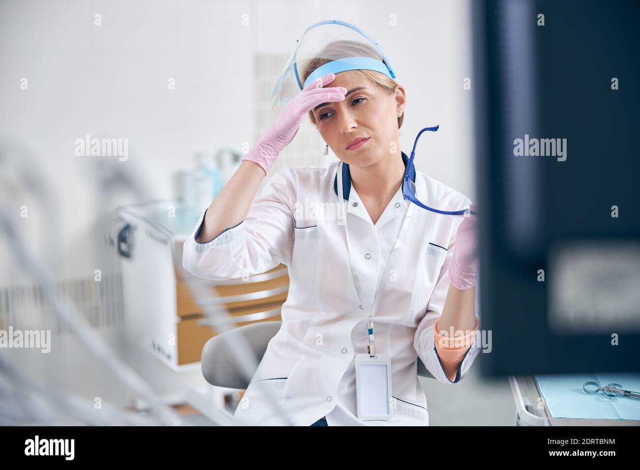 Una dentista femminile esausta dopo le procedure in ufficio Foto Stock