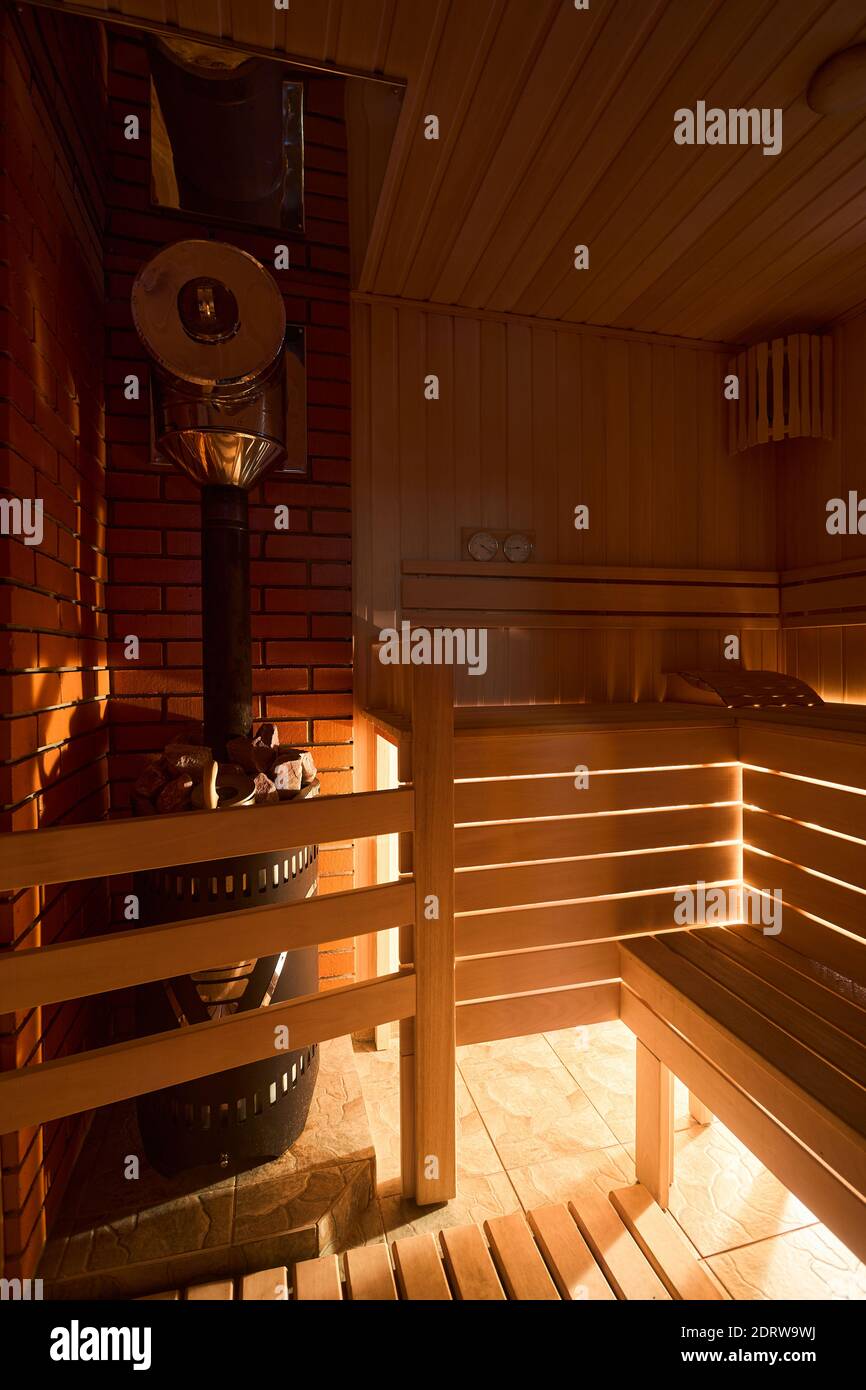Sauna russa con luce soffusa e intima da sotto fondo di panca lanterna in legno igrometro con stufa a sauna forno con Foto Stock