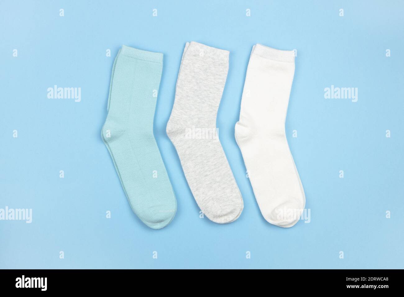 Calze colorate per bambini senza motivo, blu, grigio, bianco su sfondo blu con spazio copia, piatto, stile minimal. Concept di abbigliamento, pulizia, Foto Stock