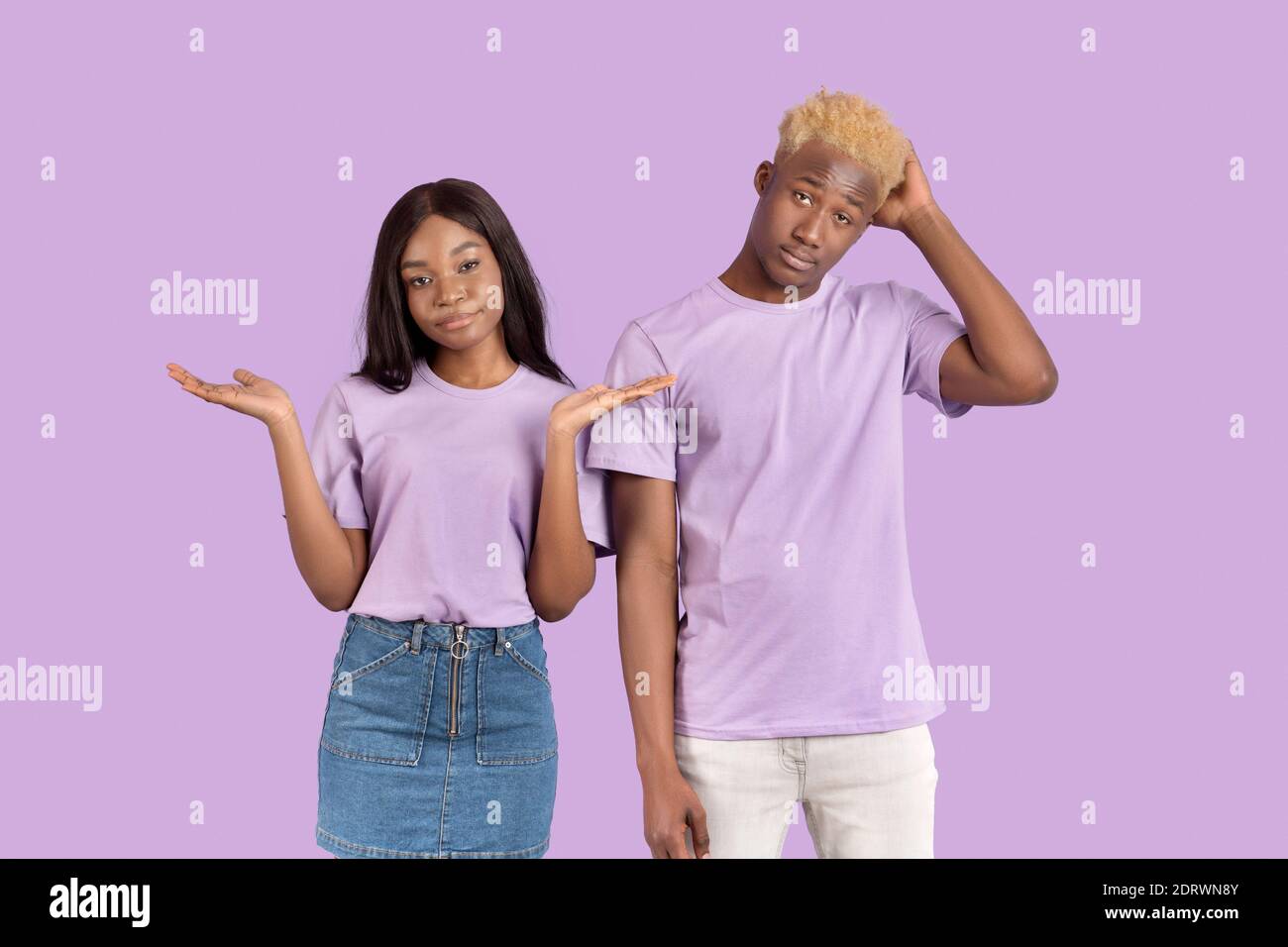 Chissà. Ritratto di giovane coppia nera che si infrangono le spalle sullo sfondo viola dello studio Foto Stock