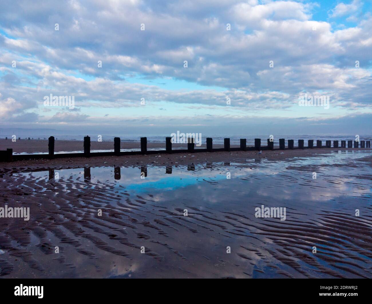 Vista invernale della spiaggia di Bridlington, una popolare località balneare nell'East Riding dello Yorkshire Inghilterra UK con il cielo riflesso nell'acqua di mare. Foto Stock
