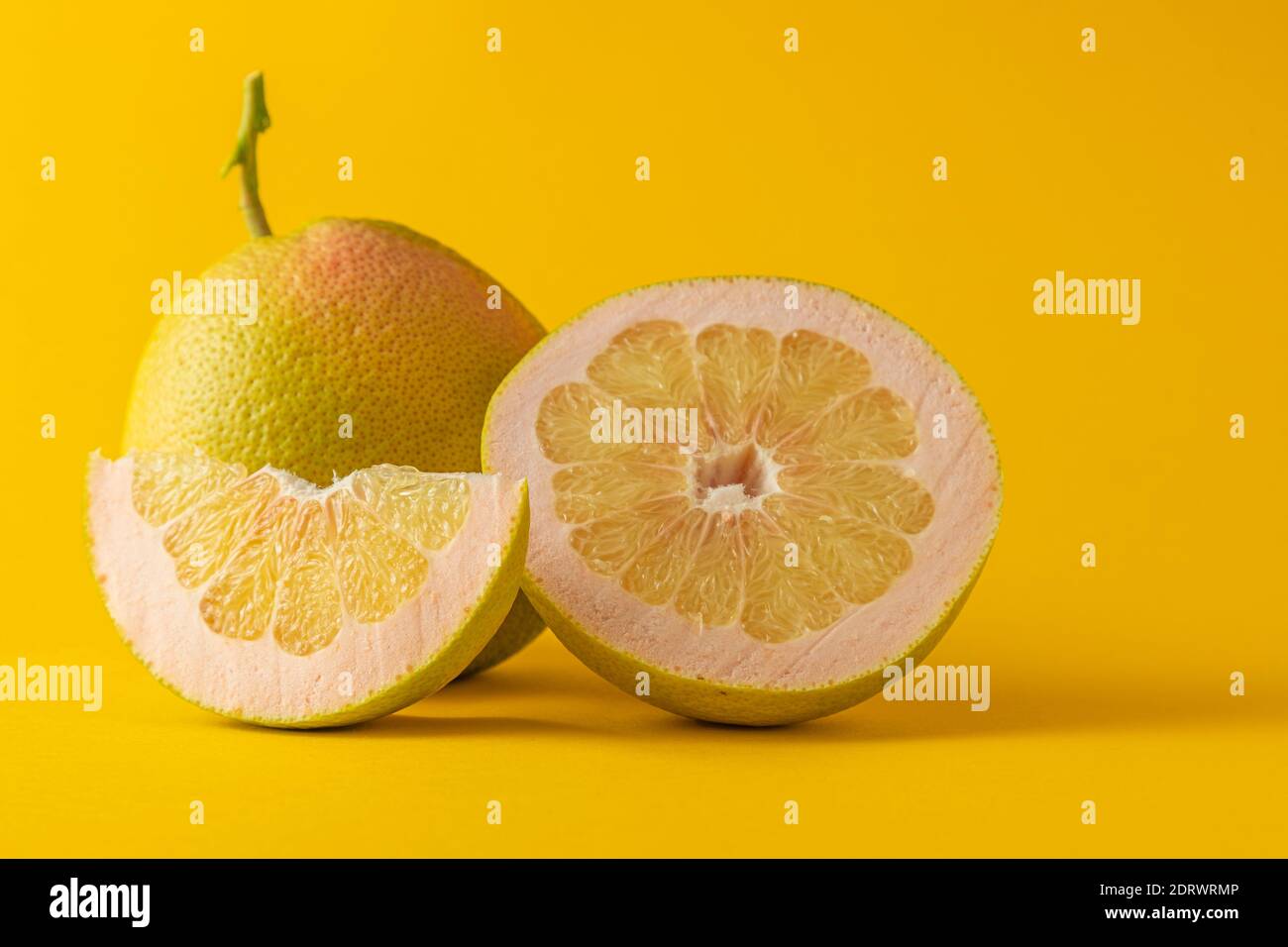 vista orizzontale in primo piano di un pompelmo mezzo e fetta di pompelmo isolata su sfondo giallo Foto Stock