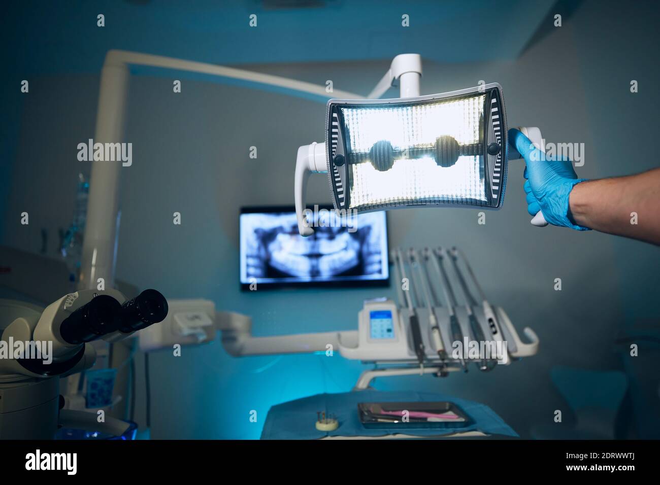 Moderna chirurgia dentale. Dentista che regola la lampada contro i raggi X dei denti in clinica dentale. Foto Stock