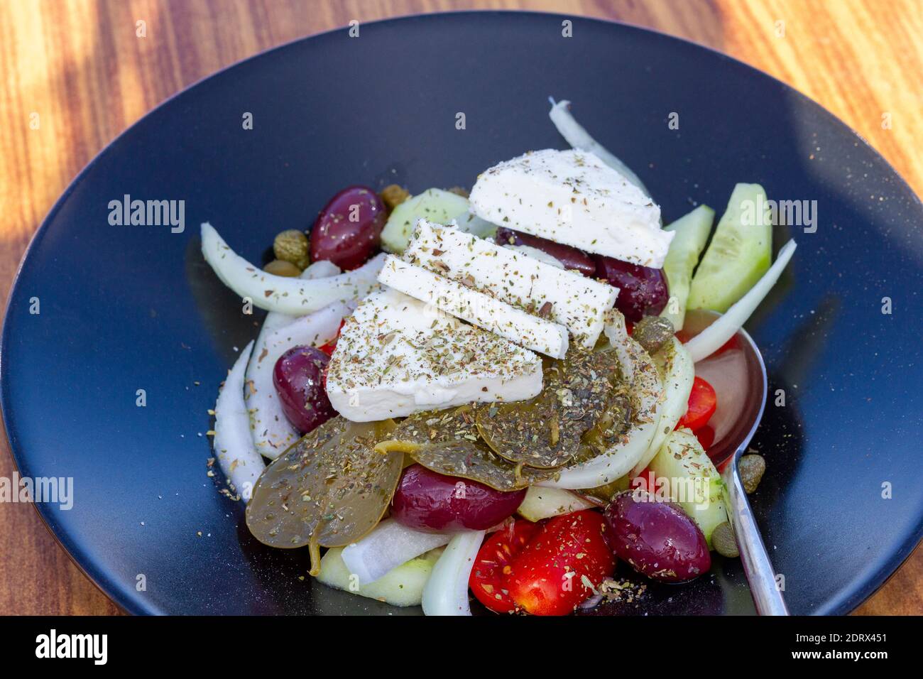 Insalata greca (choriatiki) e foglie d'uva, su un tavolo servito con cucina greca e mediterranea, nel villaggio di Oia, isola di Santorini, Grecia, Europa. Foto Stock