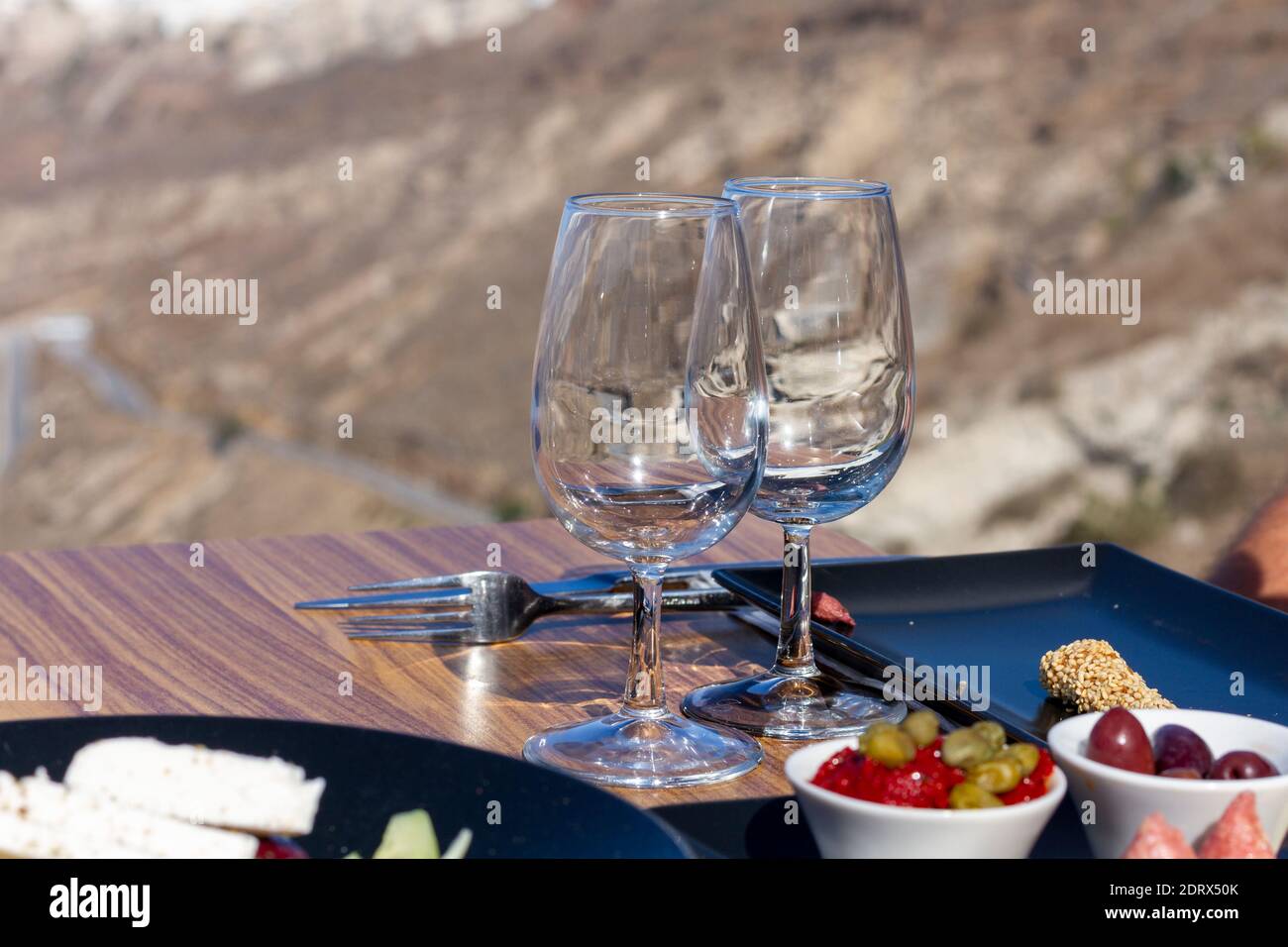 Insalata greca (choriatiki) e foglie d'uva, su un tavolo servito con cucina greca e mediterranea, nel villaggio di Oia, isola di Santorini, Grecia, Europa. Foto Stock