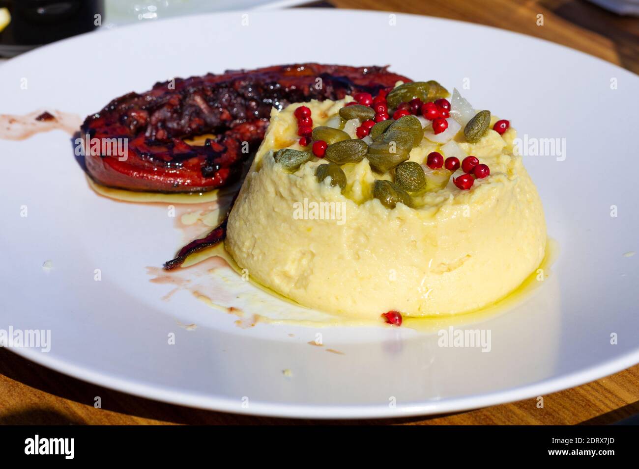 Tradizionale fava greca (purea di piselli spaccati gialli), prodotto locale dell'isola di Santorini, e polpo alla griglia, deliziosi sapori di Santorini, Grecia. Foto Stock