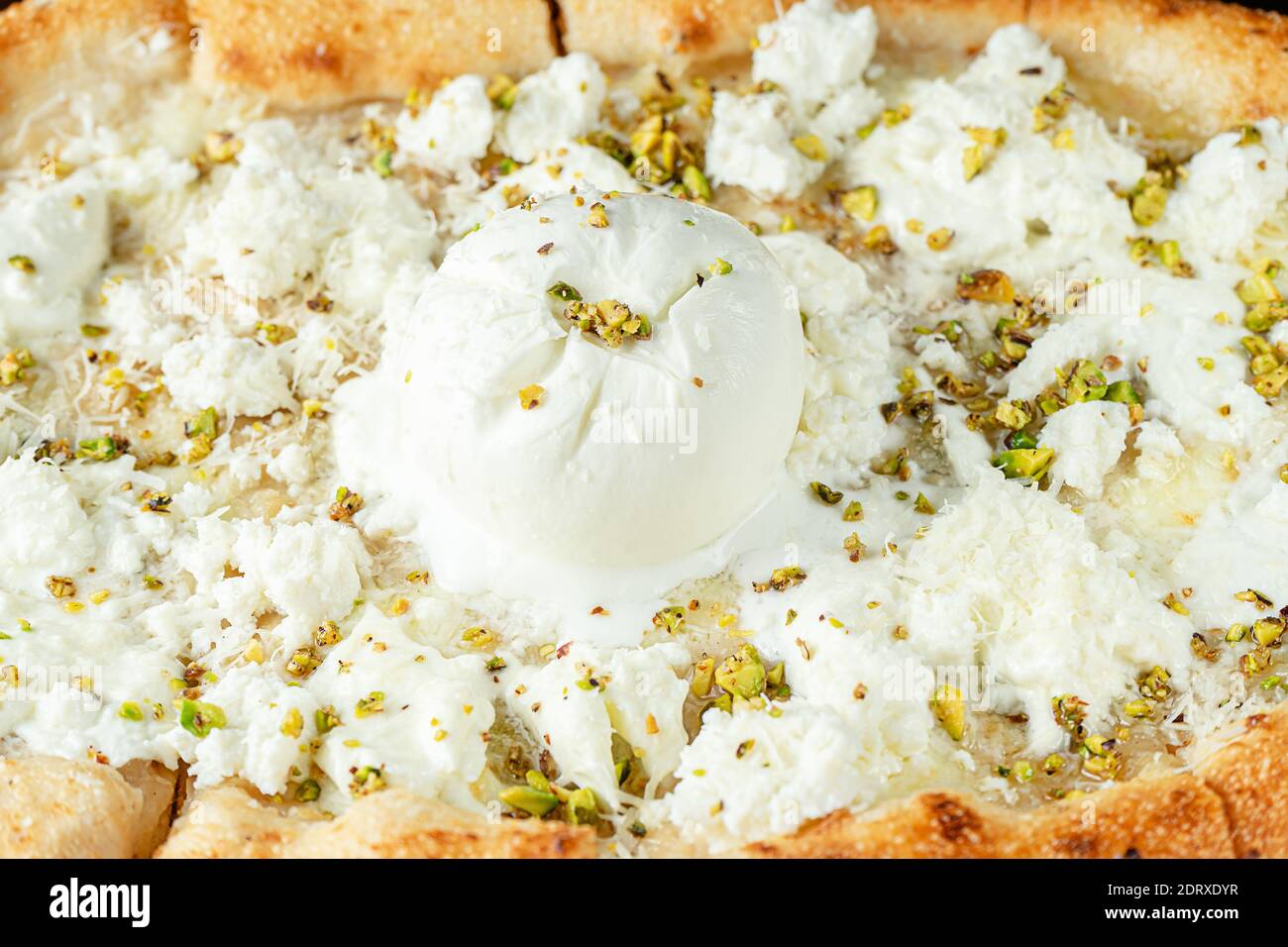 Pizza molto cheesy di sei tipi di formaggio e pistacchi. Concetto di cucina italiana. Foto Stock