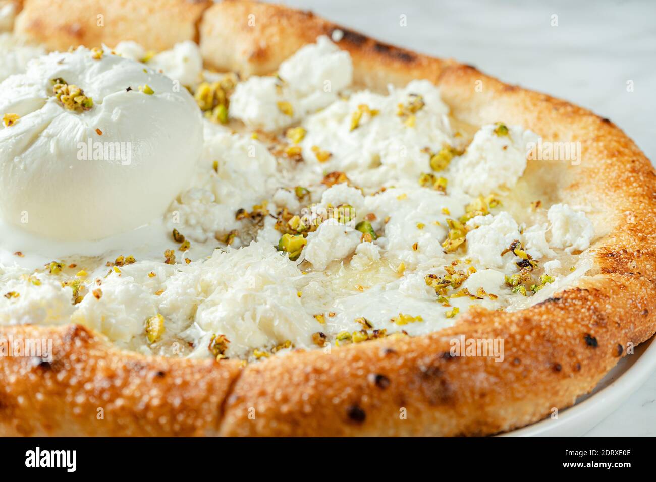 Primo piano di pizza cheesy di sei tipi di formaggio e pistacchi. Cucina italiana Foto Stock