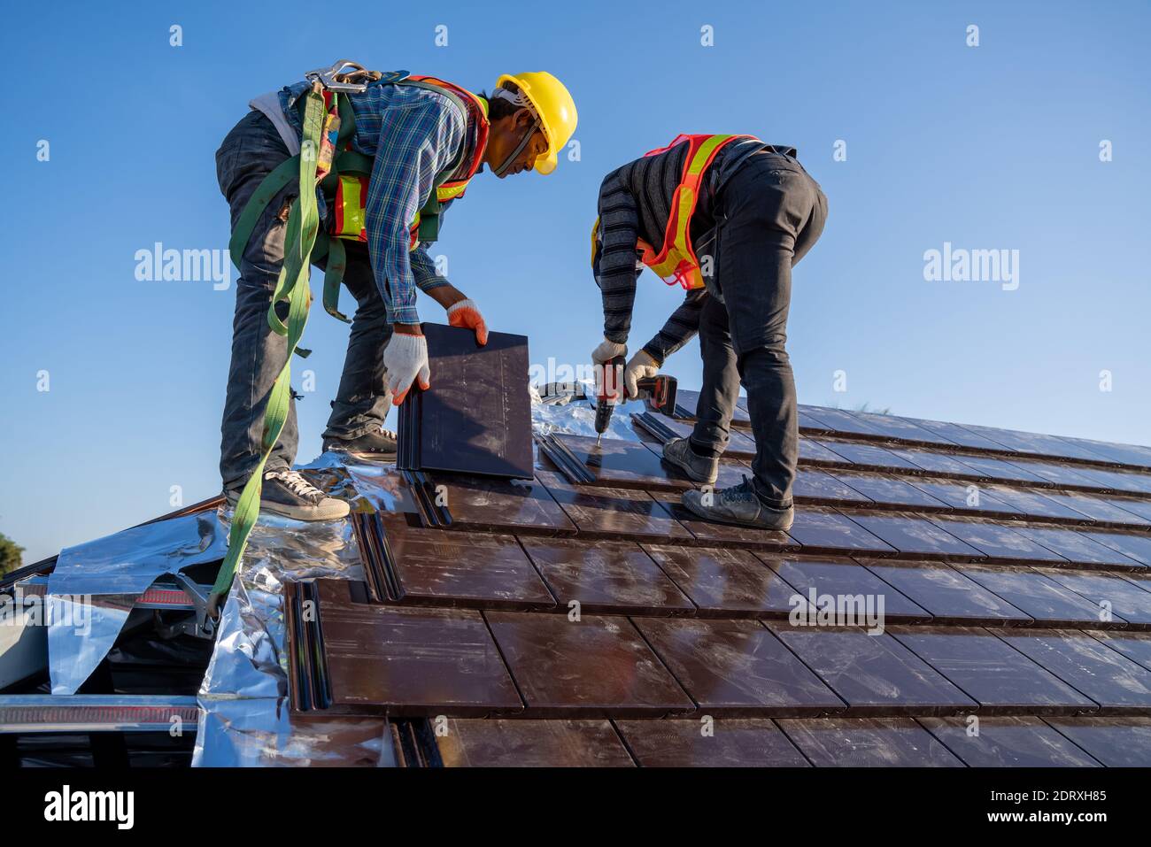 I lavoratori addetti alla costruzione installano un nuovo tetto in piastrelle di ceramica nel cantiere. Foto Stock