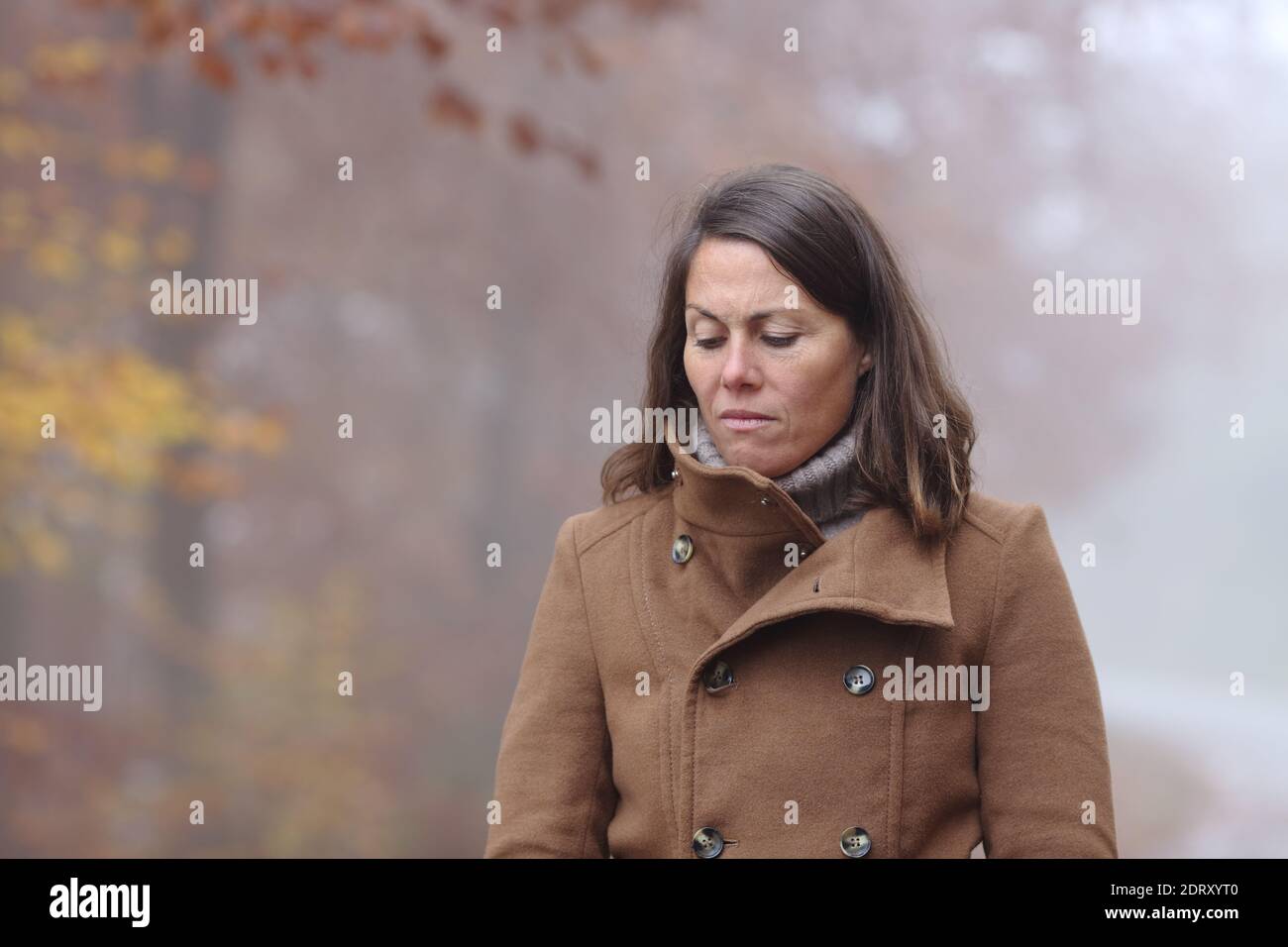 Donna triste che cammina da sola si lamenta in un parco in inverno Foto Stock