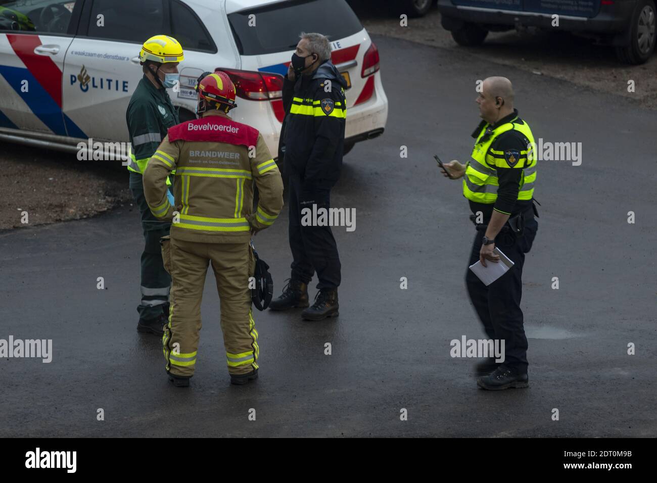 ZUTPHEN, PAESI BASSI - 08 dicembre 2020: Comandante del dipartimento dei vigili del fuoco e agenti di polizia in maschere di fronte deliberando e organizzando in una scena di incidente con Foto Stock