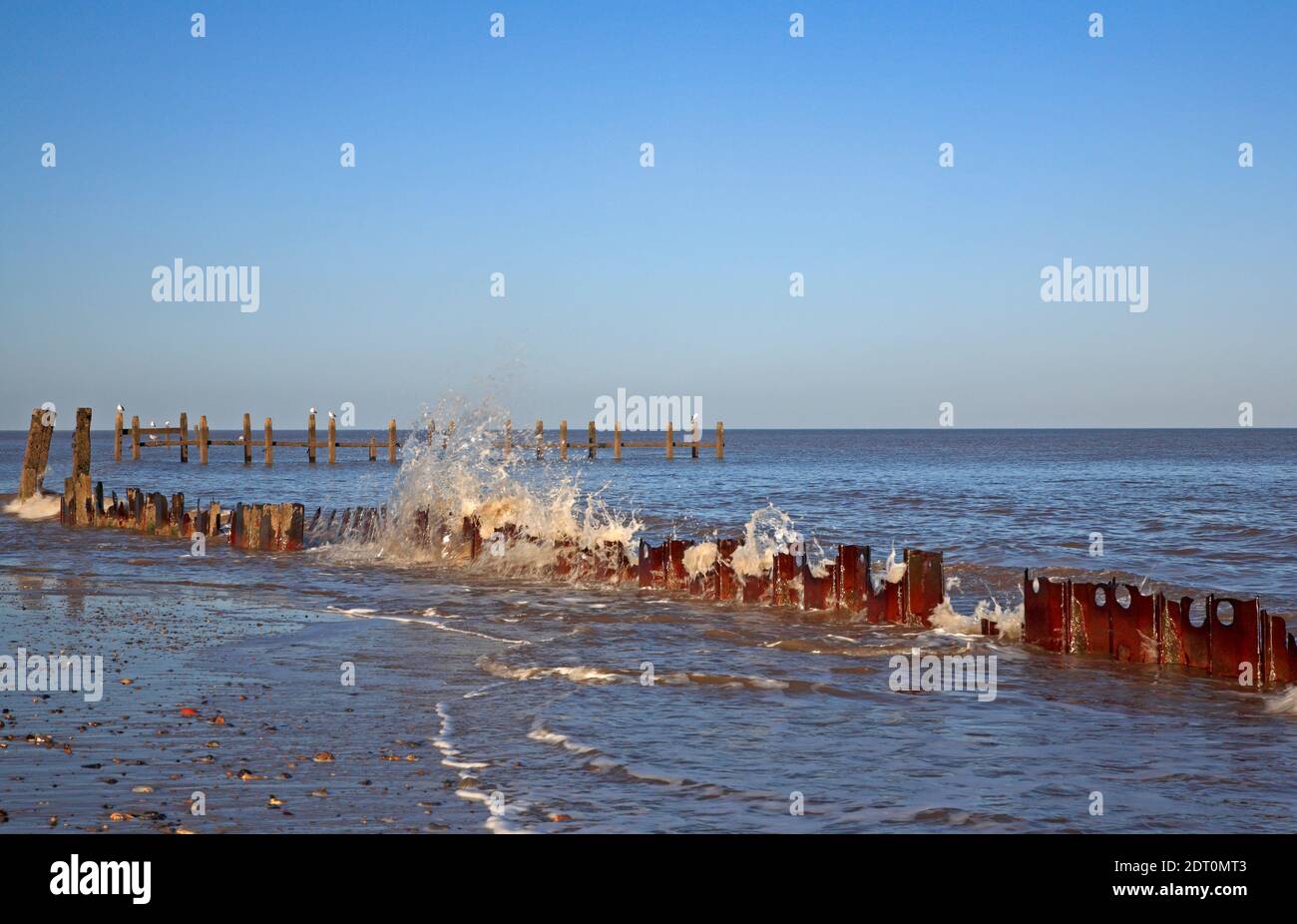Resti di una linea di casseforme metalliche dalla base di una frangiflutti decaduta rivelato a bassa marea a Cart Gap, Happisburgh, Norfolk, Inghilterra, Regno Unito. Foto Stock