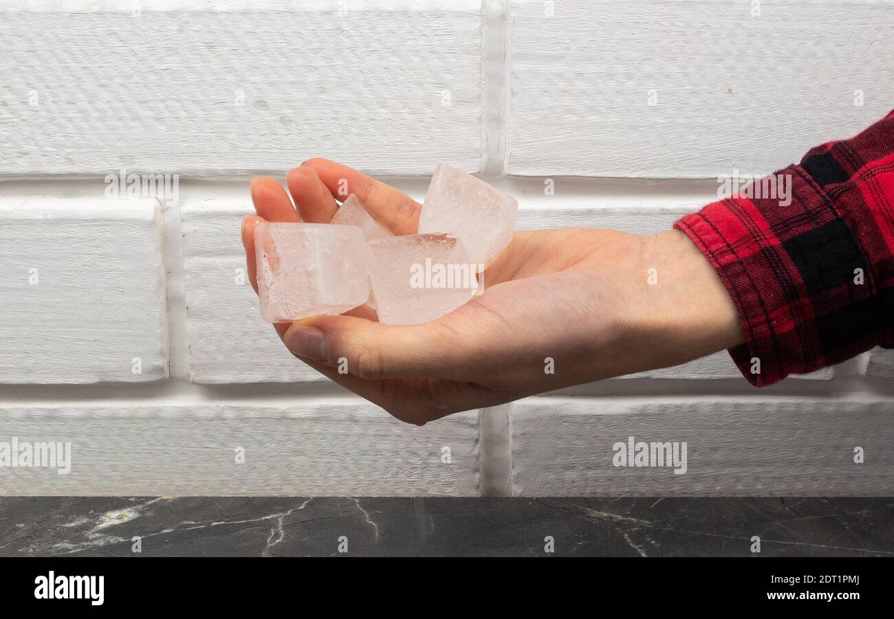 La mano femminile tiene i cubetti di ghiaccio ingrediente da cocktail Foto Stock