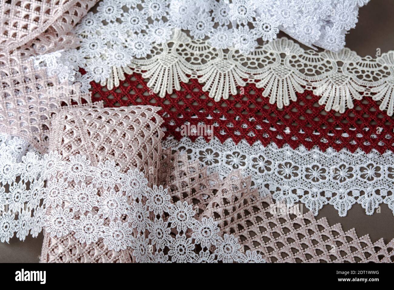 pelo di rosso, bianco. beige salpa champagne dolce lusso guipure, pizzo tessuto su sfondo grigio. da utilizzare per cucire biancheria decorazione. Foto Stock