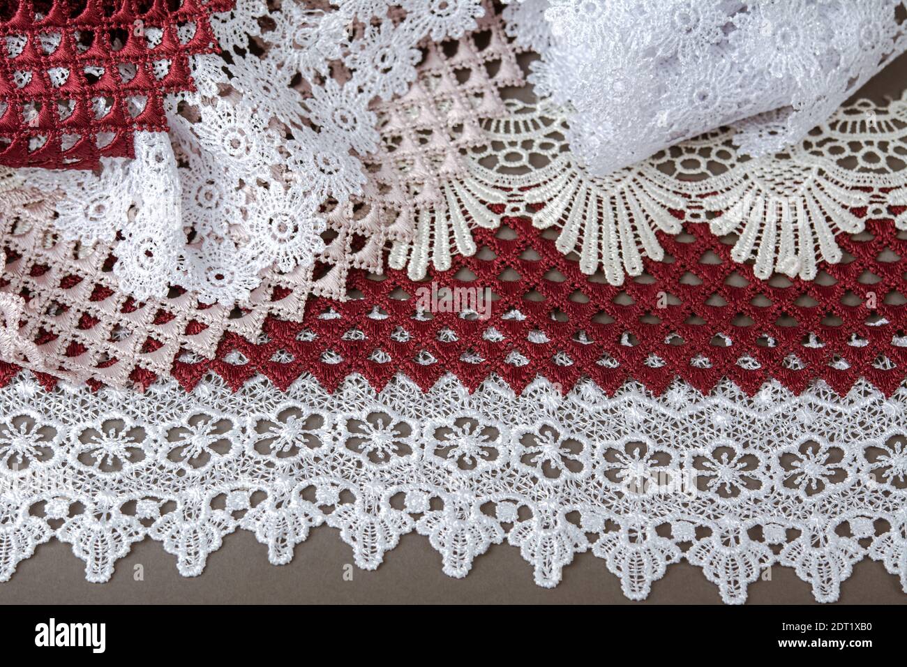pelo di rosso, bianco. beige salpa champagne dolce lusso guipure, pizzo tessuto su sfondo grigio. da utilizzare per cucire biancheria decorazione. Foto Stock