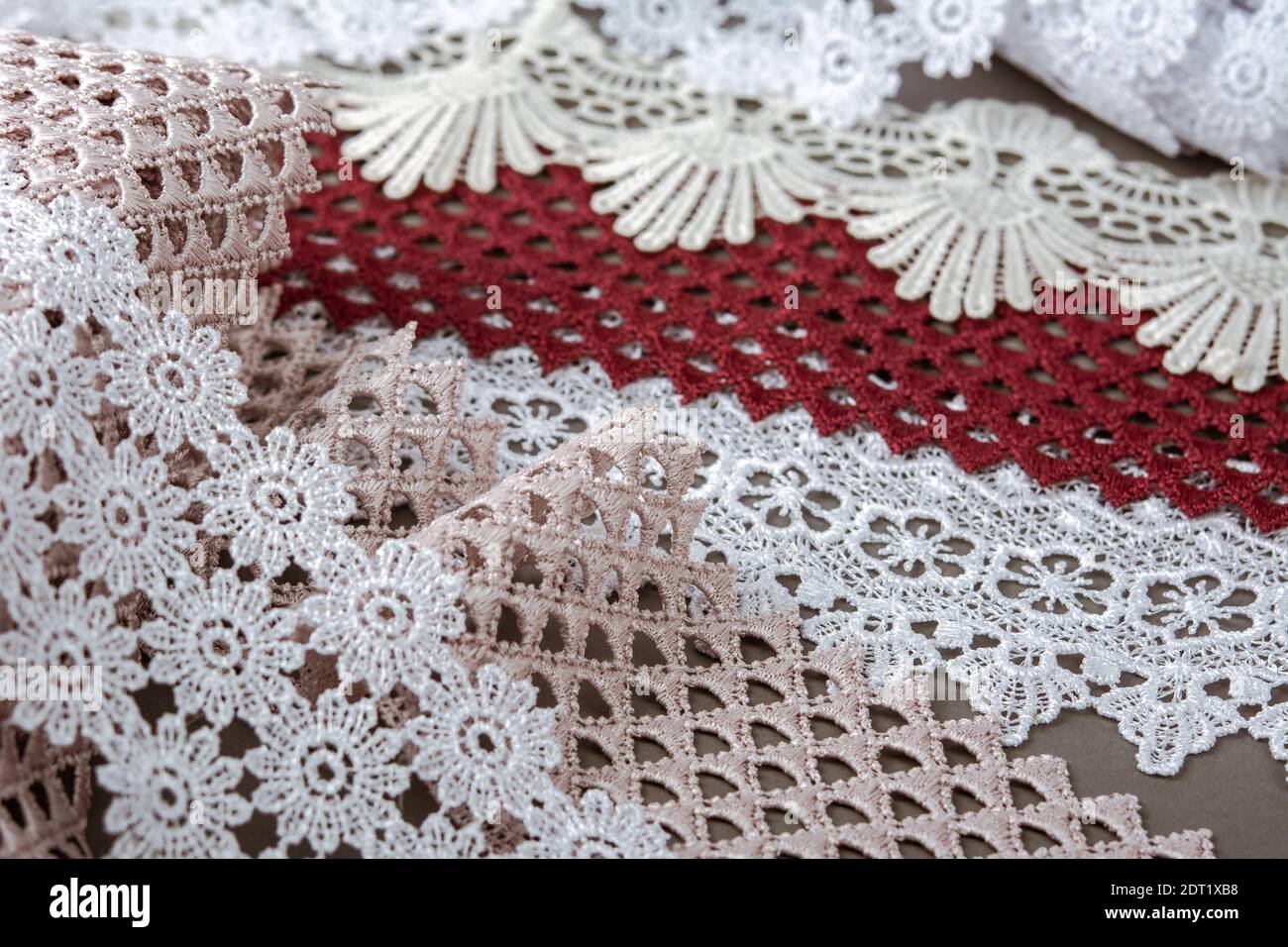 pelo di rosso, bianco. beige salpa champagne dolce lusso guipure, pizzo tessuto su sfondo grigio. da utilizzare per cucire biancheria decorazione. Foto Stock