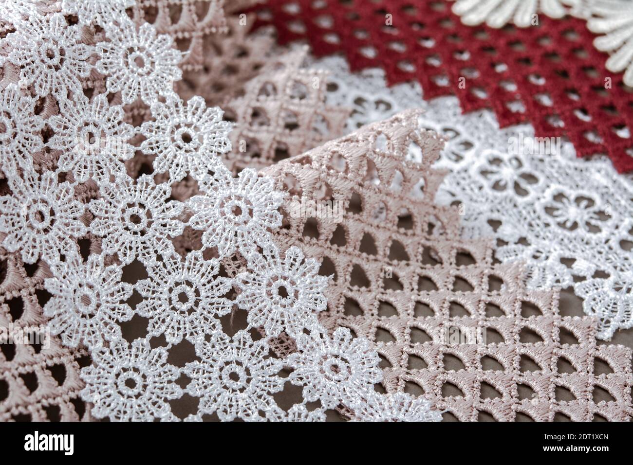 pelo di rosso, bianco. beige salpa champagne dolce lusso guipure, pizzo tessuto su sfondo grigio. da utilizzare per cucire biancheria decorazione. Foto Stock