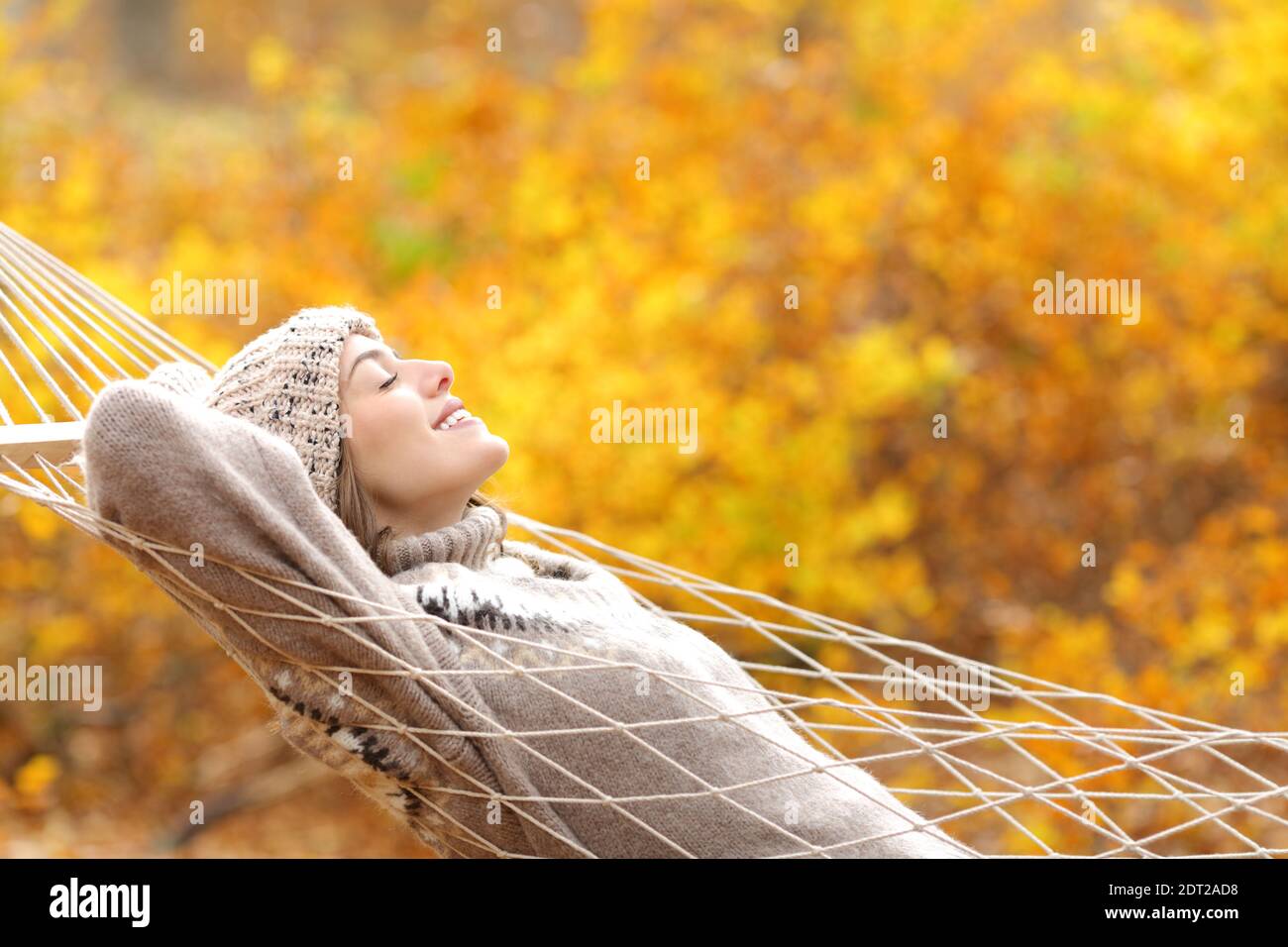 Profilo di una donna felice che giace su un amaca di corda in autunno stagione in una foresta Foto Stock