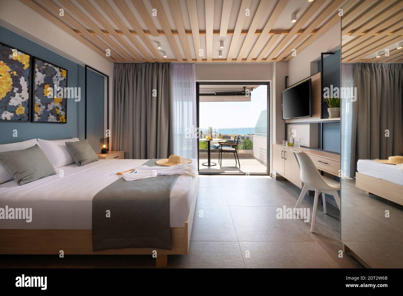 Vista laterale della moderna camera da letto in stile loft con dettagli in metallo, mobili in legno, decorazioni astratte. Appartamento dell'hotel con balcone vista mare, wi-fi francese all'aperto Foto Stock