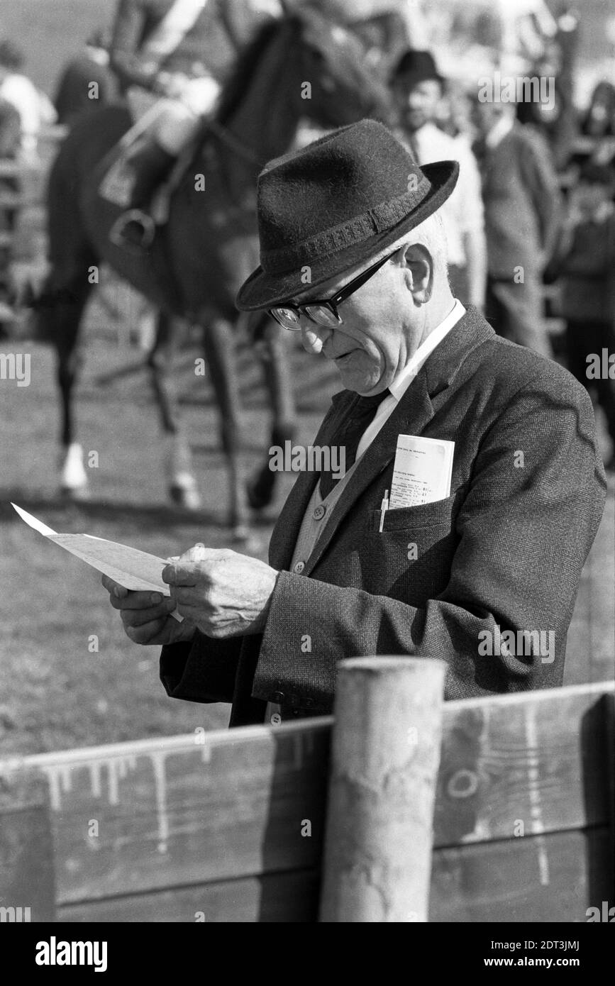 Regno Unito, Inghilterra, Devonshire, Buckfastleigh, 1972. Le gare Point-to-Point si sono svolte a Dean Court sulle paludi Dean, vicino alla A38 tra Plymouth ed Exeter. Uno spettatore che indossa un cappello trilby sta studiando la scheda da corsa. Foto Stock