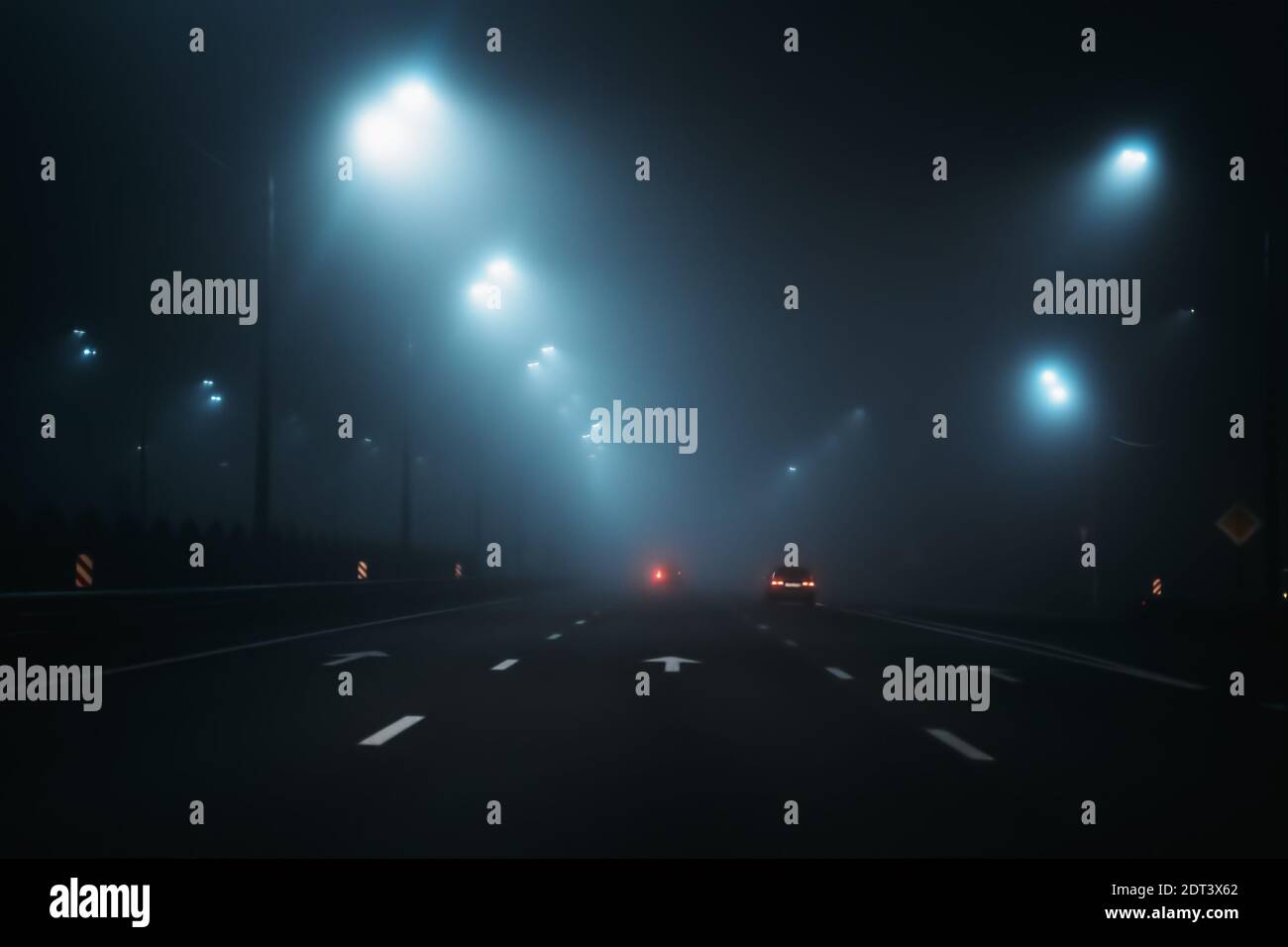 Strada buia con illuminazione della città in notte nebbiosa e nebbiosa. Foto Stock