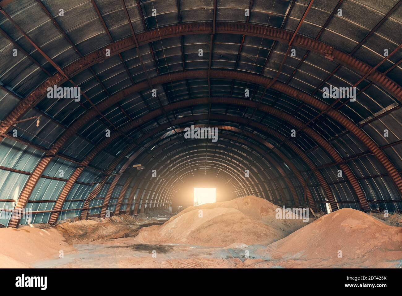 Grande hangar oblungo con mucchi di sabbia per l'industria e l'edilizia. Foto Stock