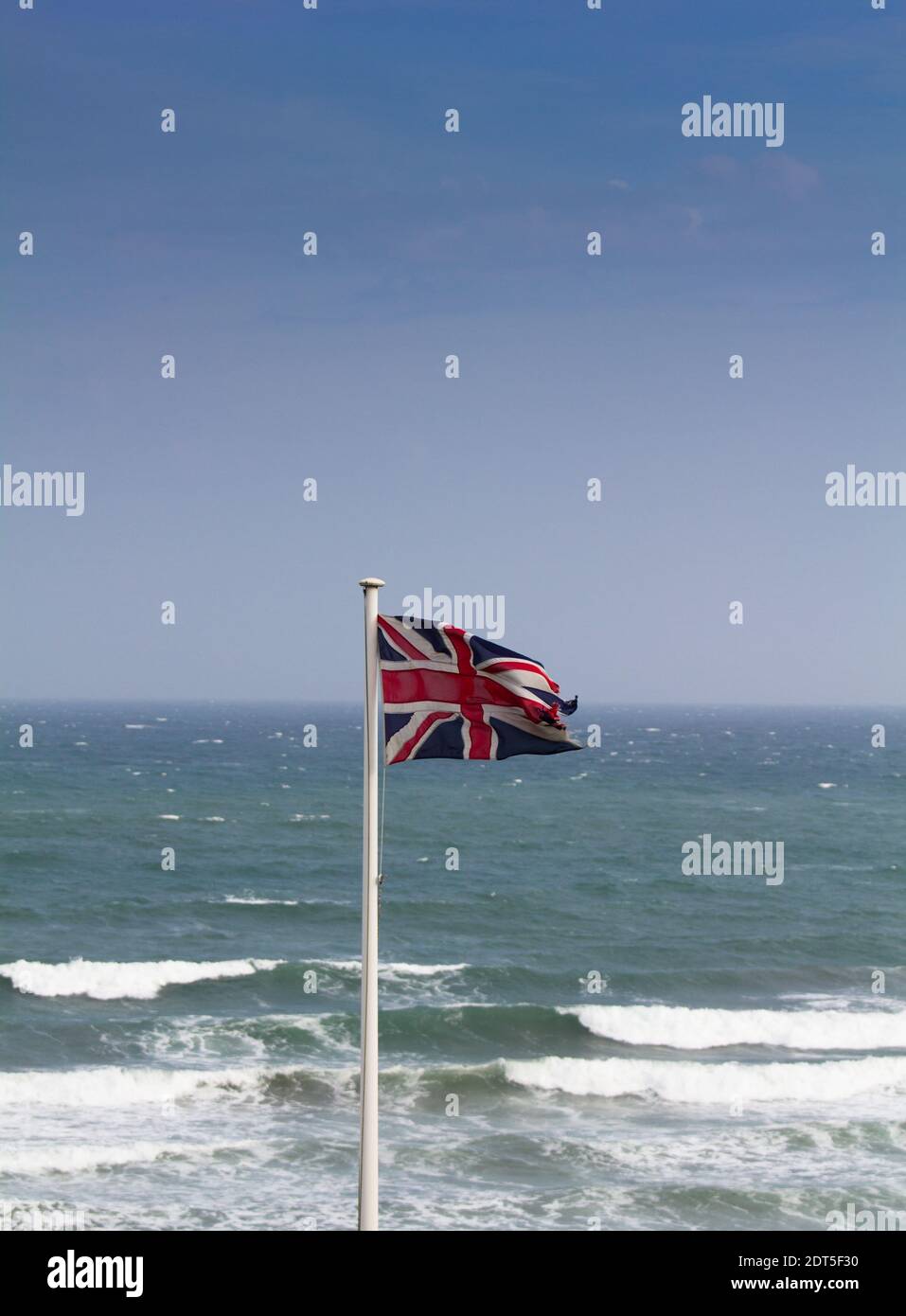 Bandiera di Unione in un forte vento onshore che domina la Manica, e una possibile tempesta di raccolta. Foto Stock