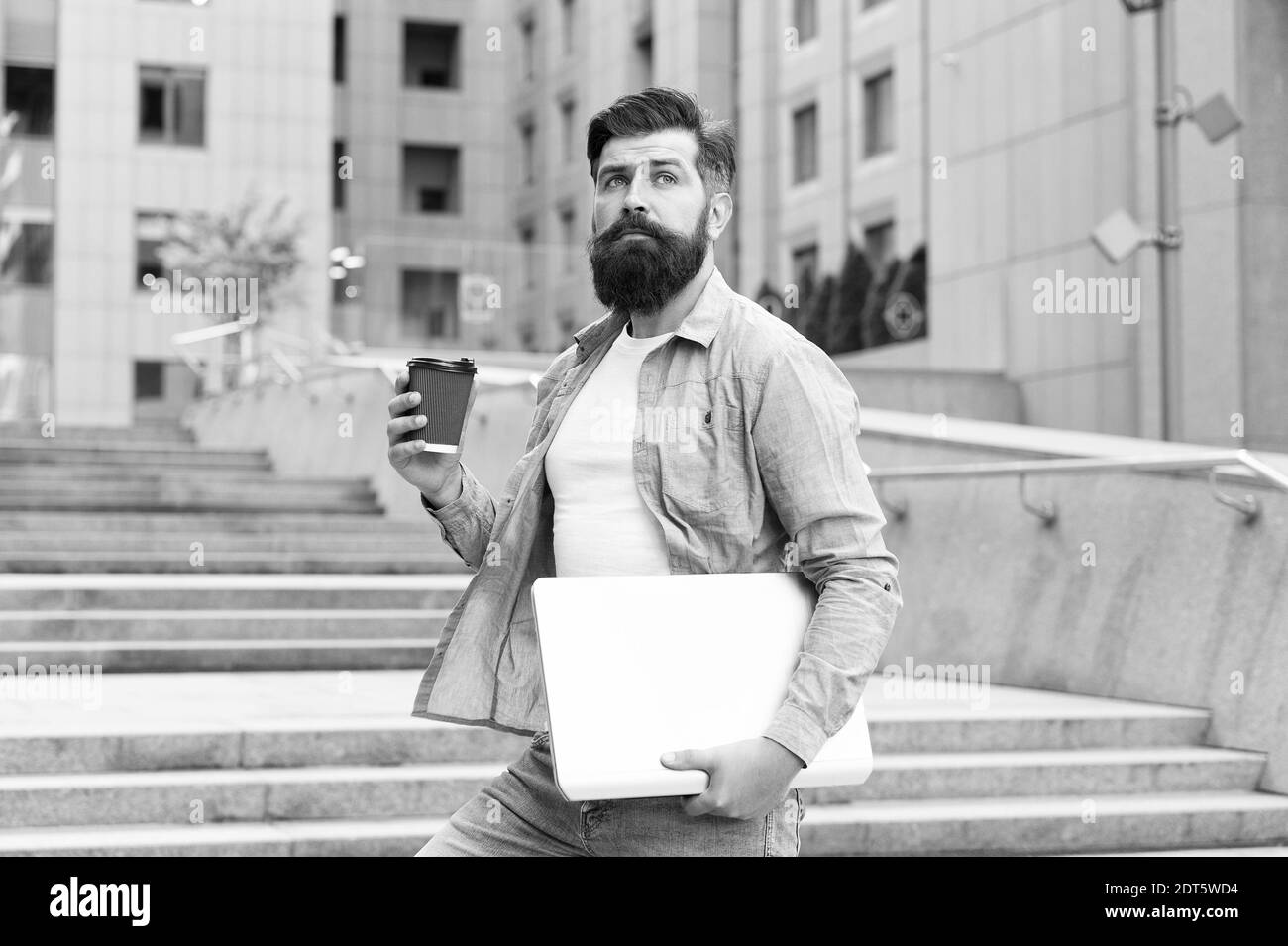 Pausa caffè. Era delle distanze sociali. Ragazzo che va a lavorare sullo sfondo urbano. Uomo con computer portatile a piedi strada vuota. Vita di affari. Vita moderna. Hipster lavoratore moderno con notebook. Tecnologia moderna. Foto Stock