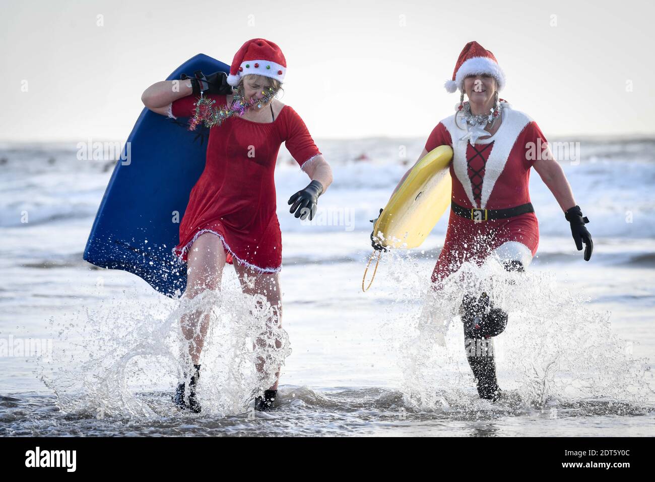 Swansea, Galles, sabato 19 dicembre 2020. Amici, Susie Davies-Lowe (a sinistra) e Sian Lewis con i loro bodyboards durante l'evento di surf Santas in mare a Langland Bay su Gower, Swansea per raccogliere fondi per Surfers contro la rete fognaria. Credito : Robert Melen. Foto Stock