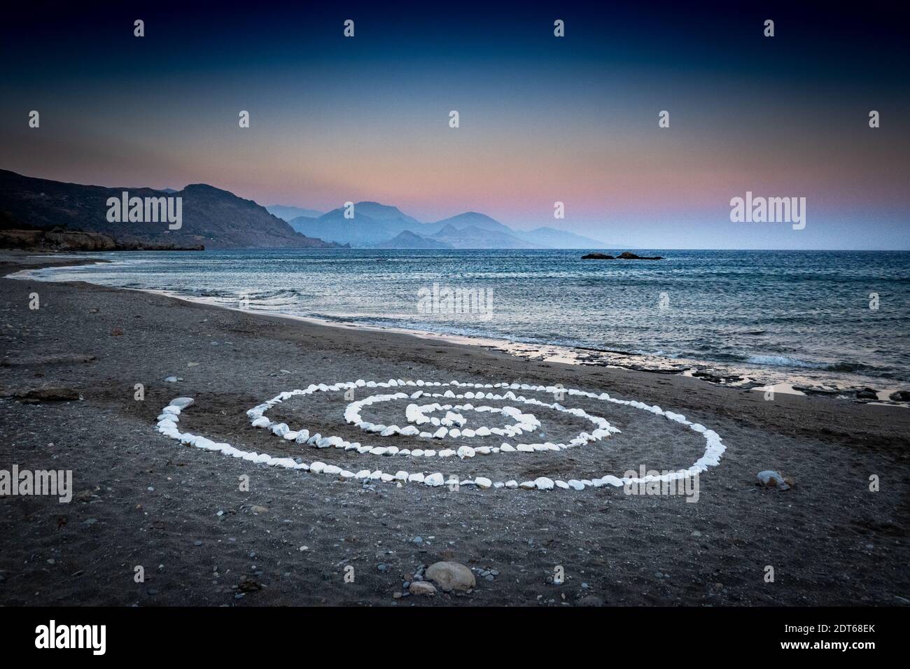Spirale di ciottoli sulla spiaggia al tramonto Foto Stock