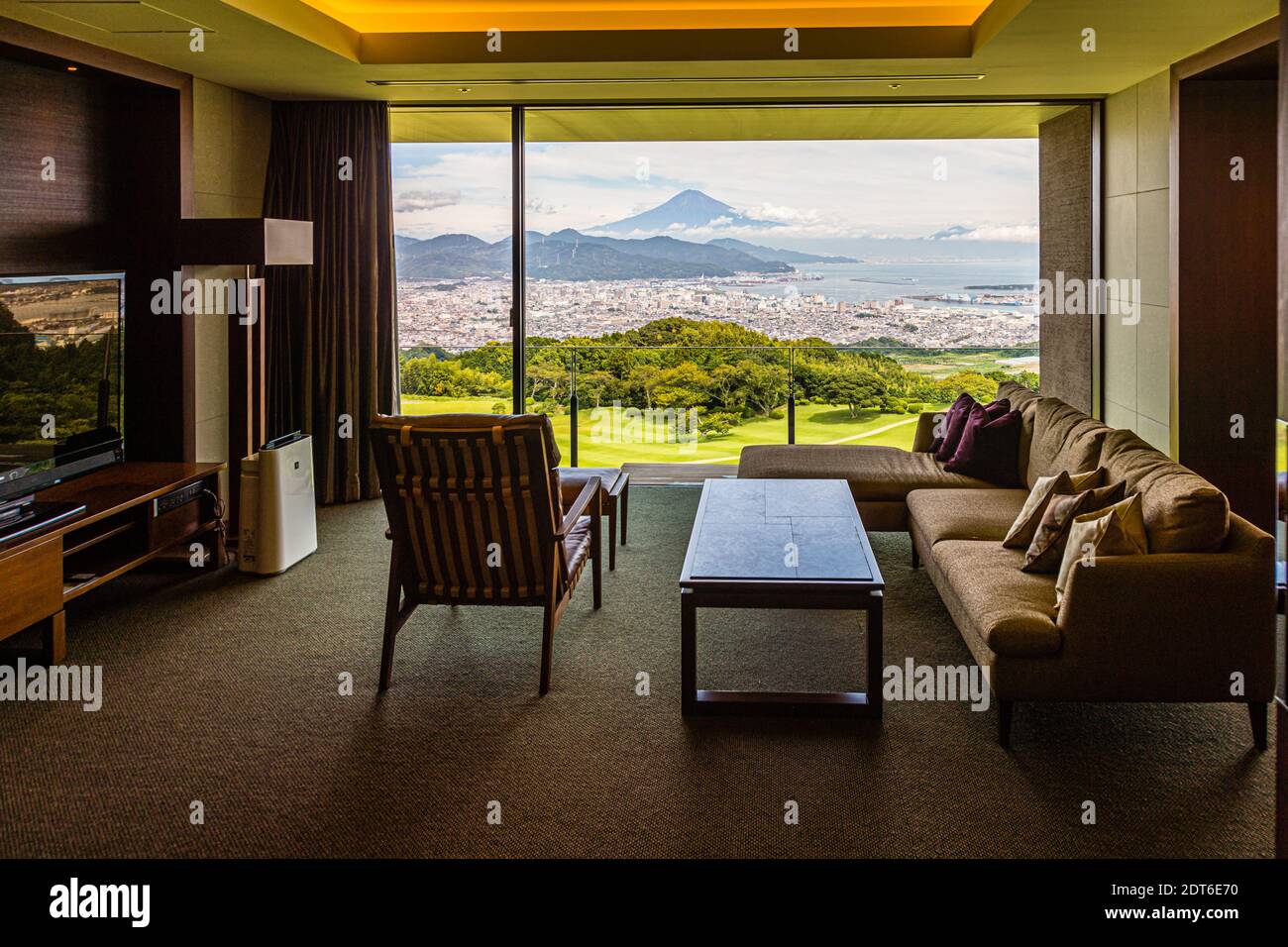 Un'area soggiorno con un divano che si affaccia su un prato ben curato verso il Monte Fuji appartiene a una suite del Nippondaira Hotel vicino a Shizuoka, in Giappone. Foto Stock