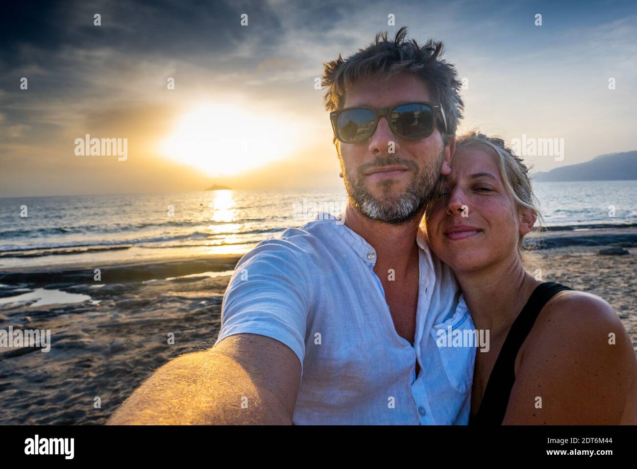 Felice coppia che parla selfie sulla spiaggia durante il tramonto Foto Stock