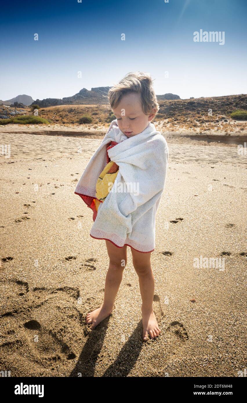 Bambino avvolto in un asciugamano sulla spiaggia Foto Stock