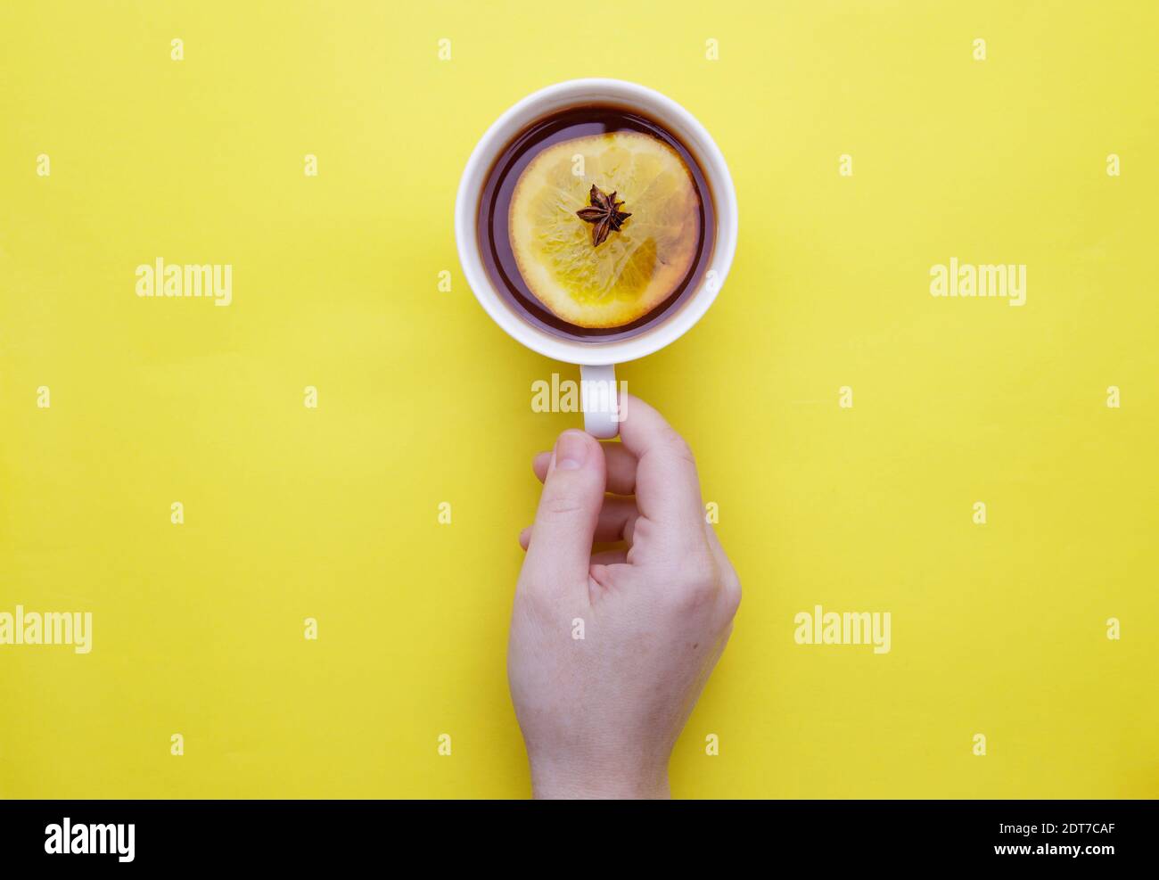 mano femminile che tiene una tazza di frutta tè invernale con limone e anice Foto Stock