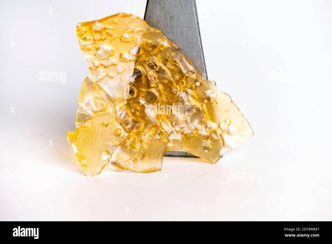 Macro dettaglio del concentrato di olio di cannabis aka shatter isolato sopra sfondo bianco Foto Stock