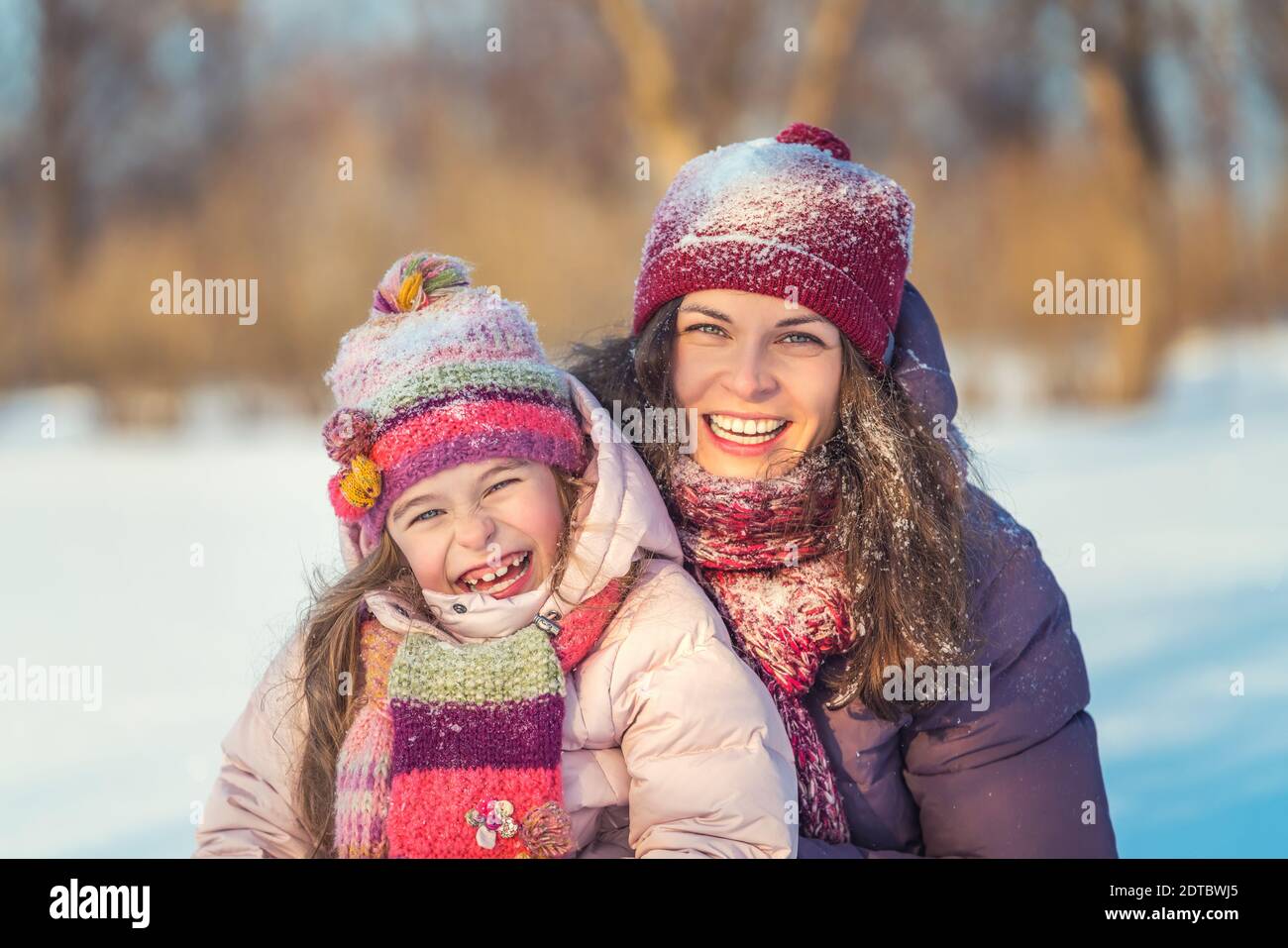 Bambina e sua madre giocano all'aperto durante il giorno di sole invernale. Concetto attivo di vacanze invernali. Foto Stock