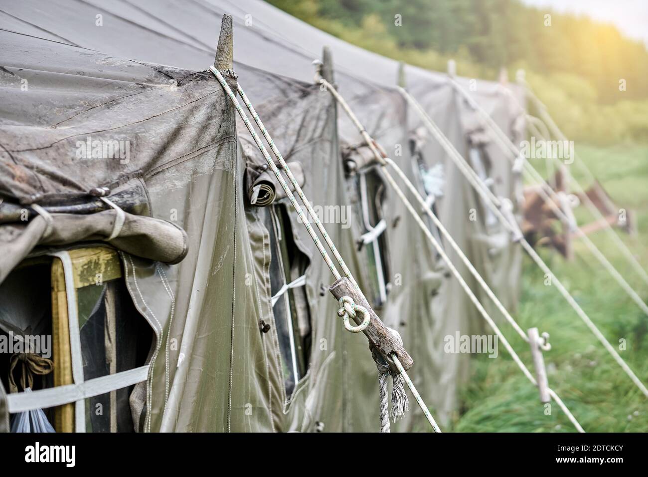 Grande campo militare tenda con finestre e una stufa sul prato nella foresta. Primo piano del finestrino della tenda Foto Stock