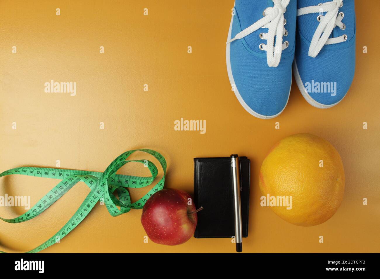 Notebook con frutta e sneakers vista dall'alto. Cuffie per lo sport. Cornice per il progettista. Dieta, sport, autodisciplina. Foto Stock