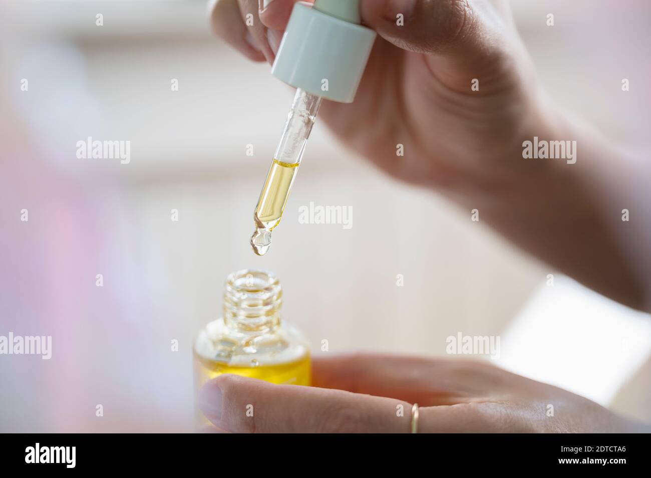 Le mani della donna tengono il flacone di olio CDB e il contagocce Foto Stock