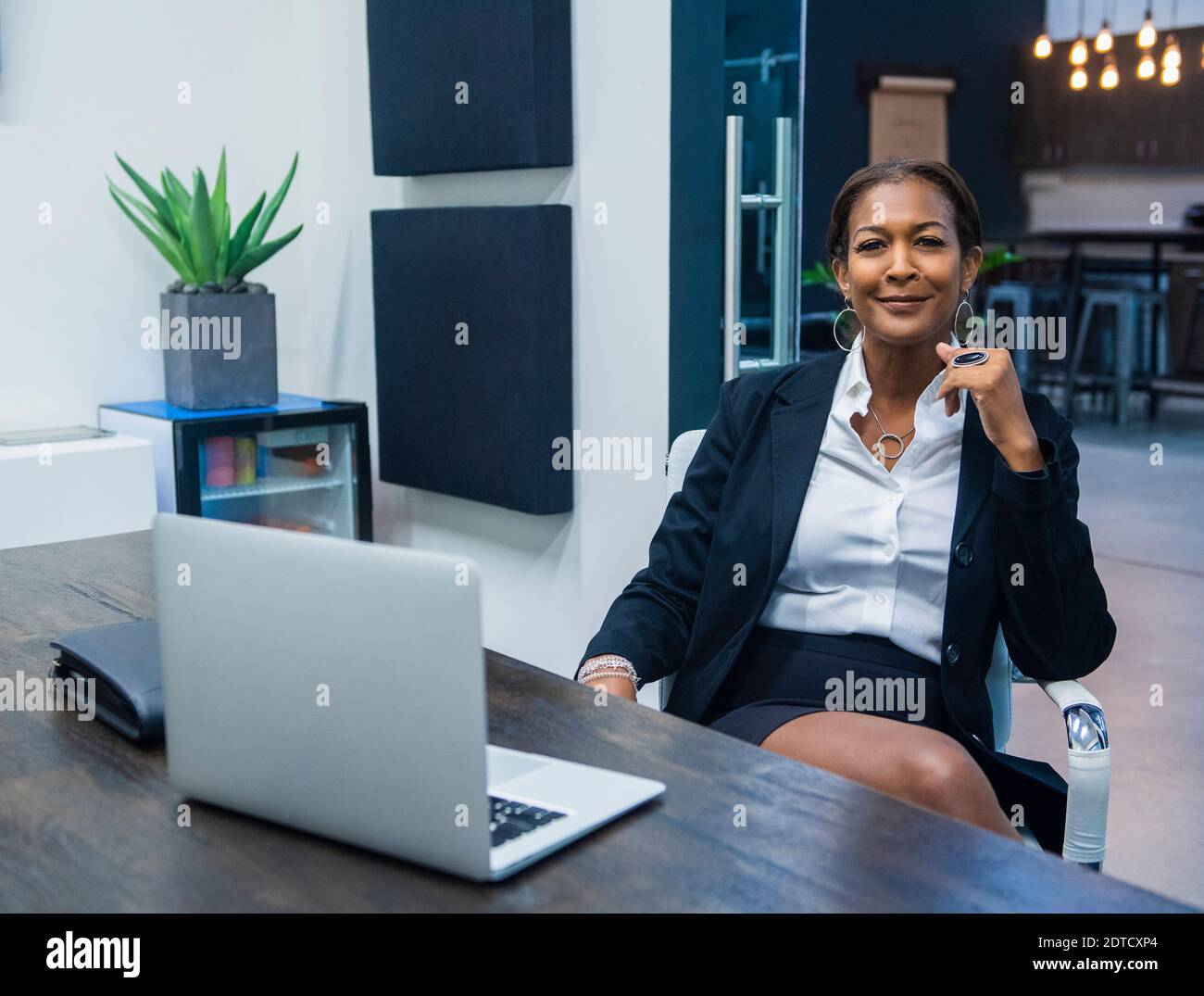 Ritratto di sorridere imprenditrice seduto alla scrivania in ufficio Foto Stock