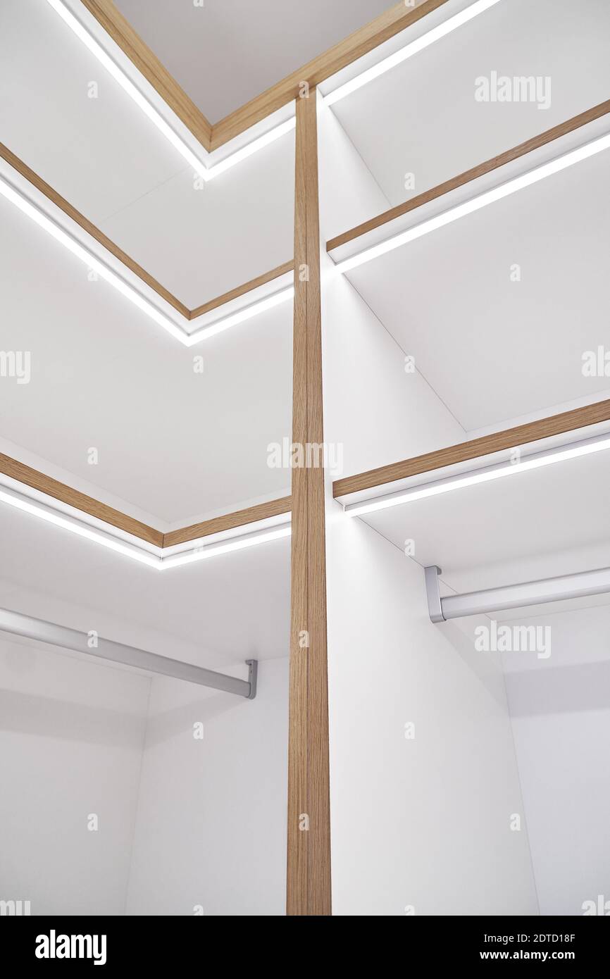 Elegante scaffale bianco con illuminazione a LED. Scaffalatura di pannelli laminati con bordi e facce di cassetti in fogli di compensato di quercia impiallacciata in camino cl Foto Stock