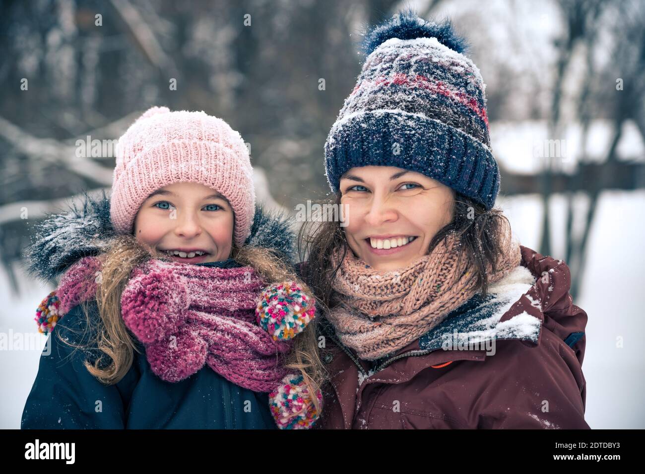 Bambina e sua madre giocano all'aperto durante il giorno d'inverno. Concetto attivo di vacanze invernali. Foto Stock