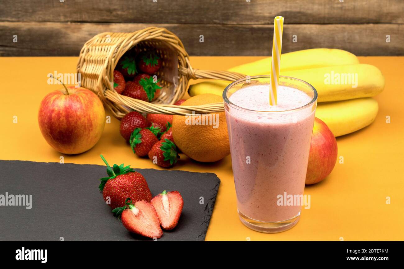 Frullato di frutta con fragole e banana. Vista laterale del milkshake con fragole, banana, mele, arancio. Delizioso e fresco cocktail di frutta Foto Stock