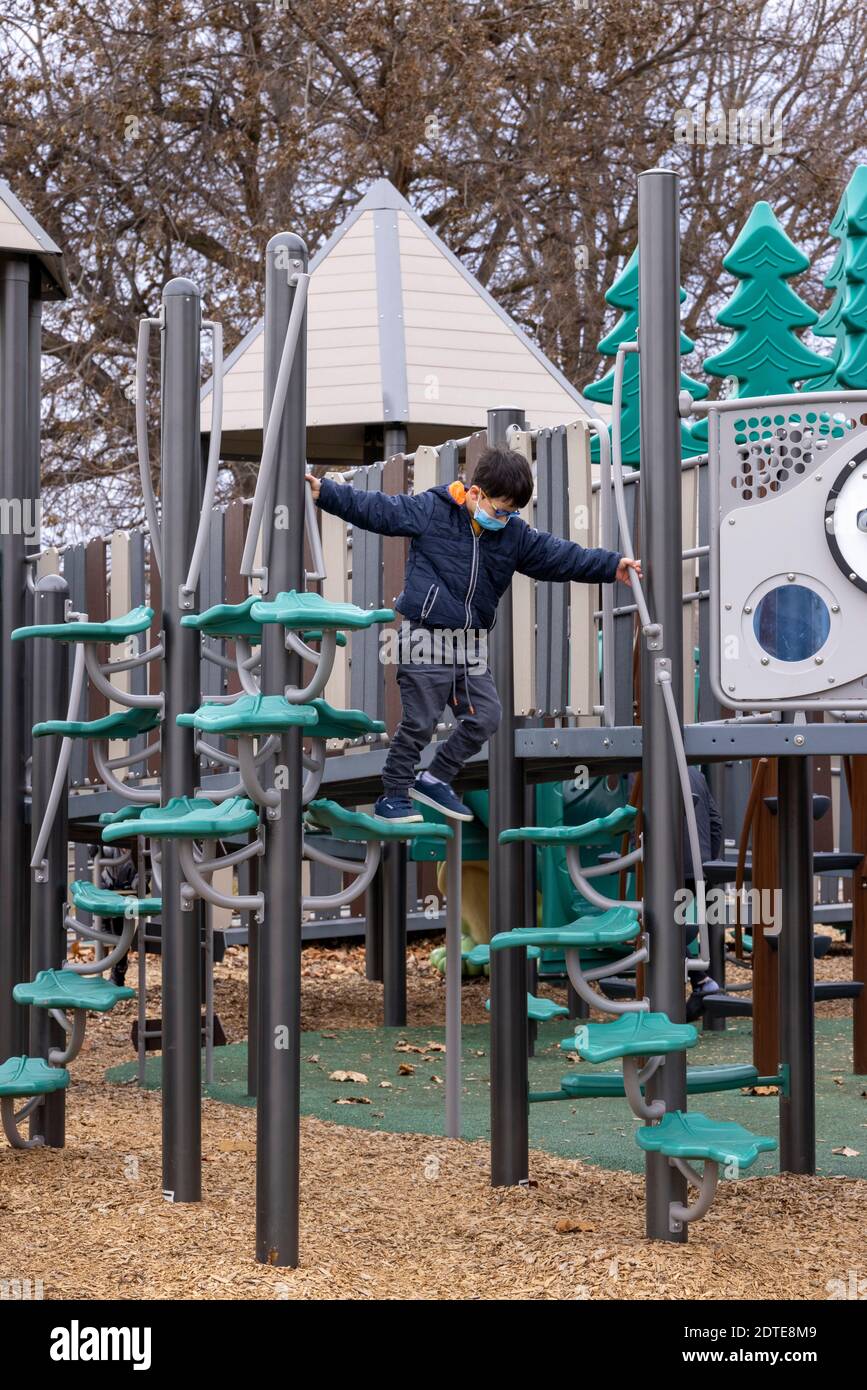 ragazzo su telaio di arrampicata guardando nel parco giochi con maschera on Foto Stock