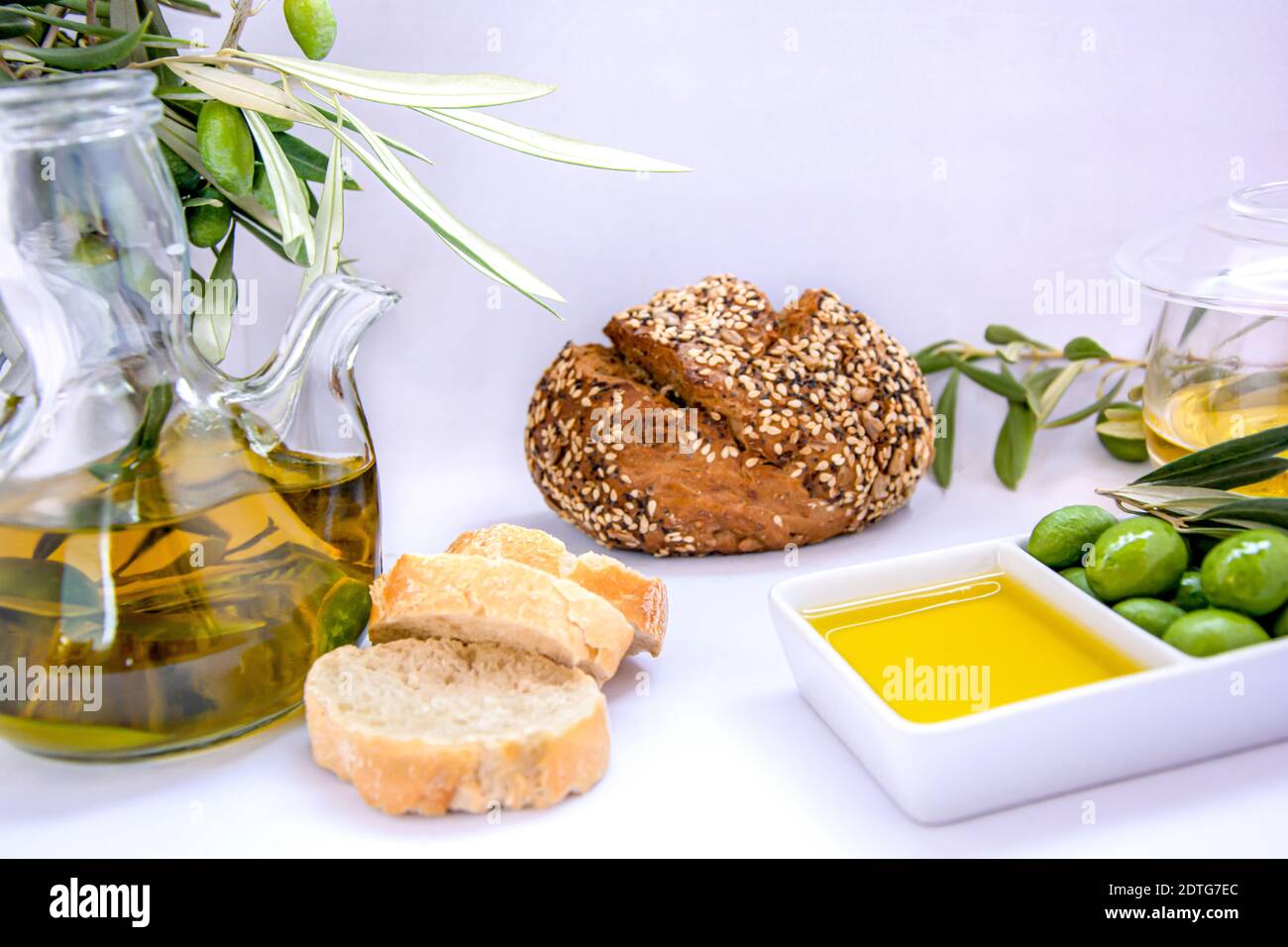 Olio vergine d'oliva puro con olive, rametto d'oliva, olivo e pane su sfondo chiaro Foto Stock