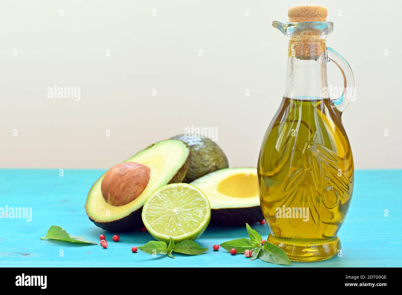 Concetto con avocado tagliato, metà di un calce e una bottiglia di olio d'oliva su fondo bianco e blu. Foto Stock