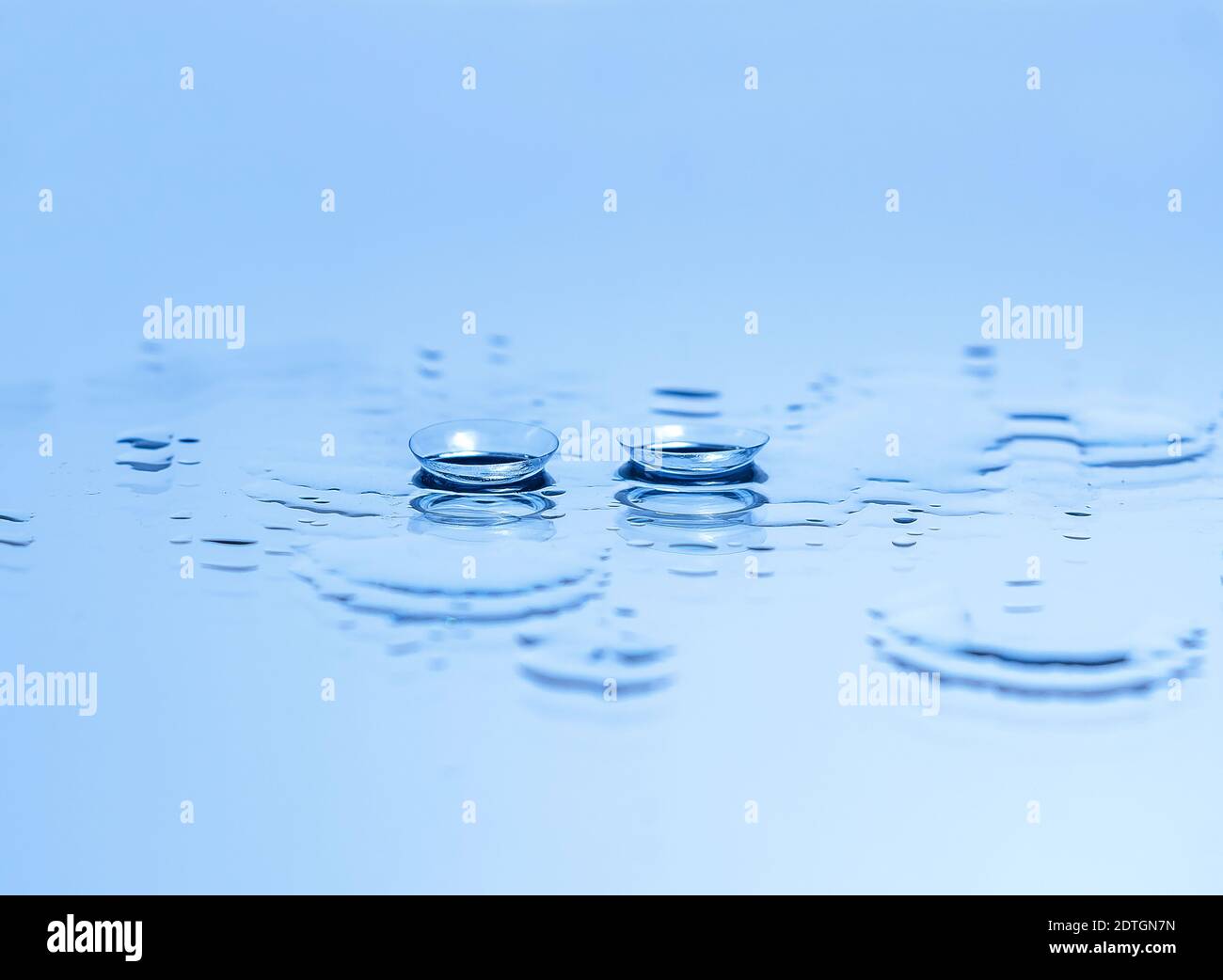 Lenti a contatto per gli occhi sul vetro tra le gocce d'acqua in Blu.  Apparecchiature ottiche Foto stock - Alamy