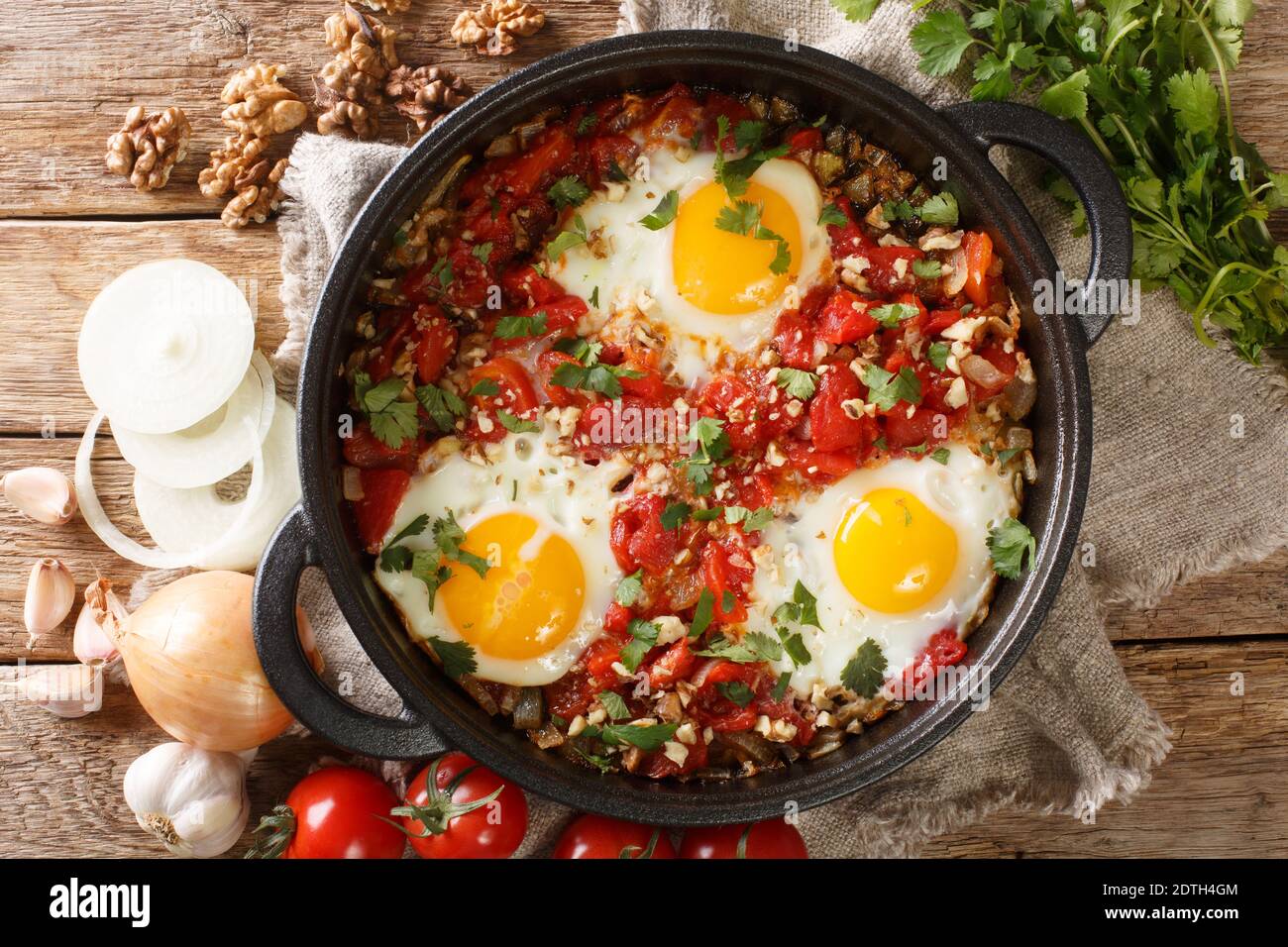 Chirbuli è un piatto di base del tavolo georgiano per la colazione composto da uova fritte con pomodori, cipolle e noci primo piano in una padella sul tavolo. Foto Stock