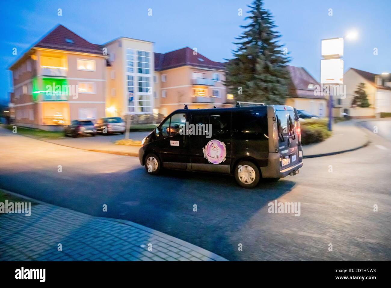 21 dicembre 2020, Brandeburgo, Jüterbog: Il minibus delle clown cliniche dell'associazione Potsdam "Lachen hilft e.V." (Il laughter aiuta) arriva per un concerto di Natale in un centro di anziani a Jüterbog. Secondo Tanja Selmer (Clown Tiffy), i clown ambulanti si sono esibiti con due squadre di cinque clown ciascuna di fronte a residenti di diverse istituzioni sociali e mediche per fornire una vicinanza emotiva durante questo periodo difficile. Un'esenzione dal reparto sanitario ha permesso ai clown, dopo un precedente test Corona e nel rispetto delle norme igieniche, di riunirsi e di svolgere le loro attività Foto Stock